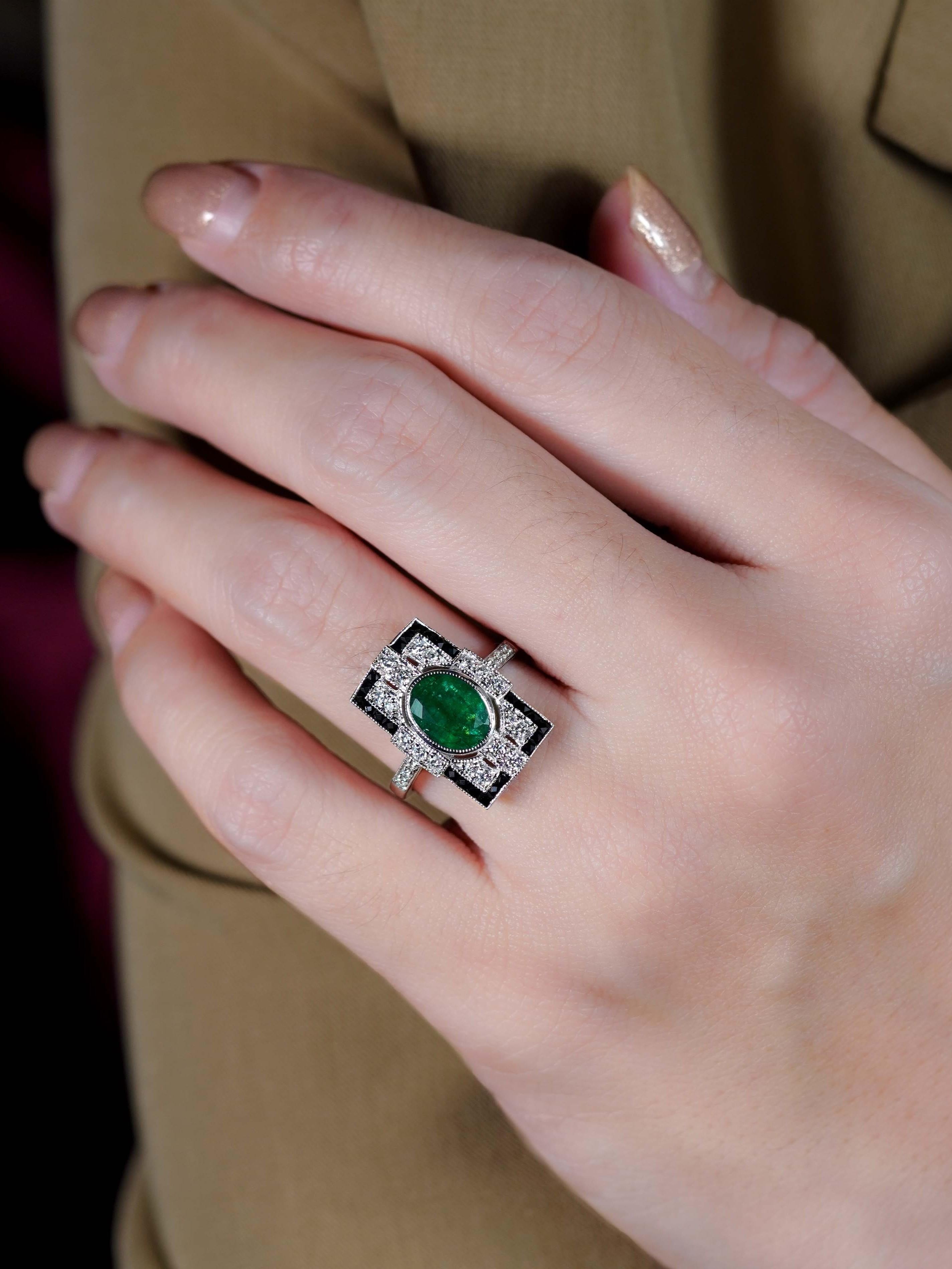 A vivid 1.8 carat oval emerald bezel-set at the center, radiating timeless elegance. A sparkling diamonds surrounds the emerald, adding brilliance and contrast. Framed by sleek black onyx in a bold rectangular shape, it captures true vintage
