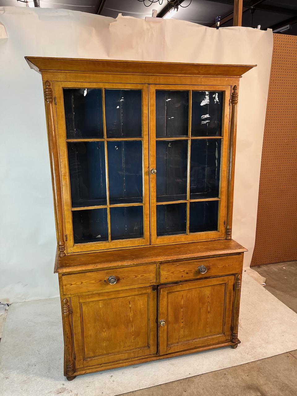 Exemple remarquable d'une armoire classique à dos d'âne.  Pin avec intérieur peint.  Parfait pour présenter de la porcelaine, des livres ou toute autre collection.  Deux pièces avec une base d'armoire à deux tiroirs et deux portes. Verre original.