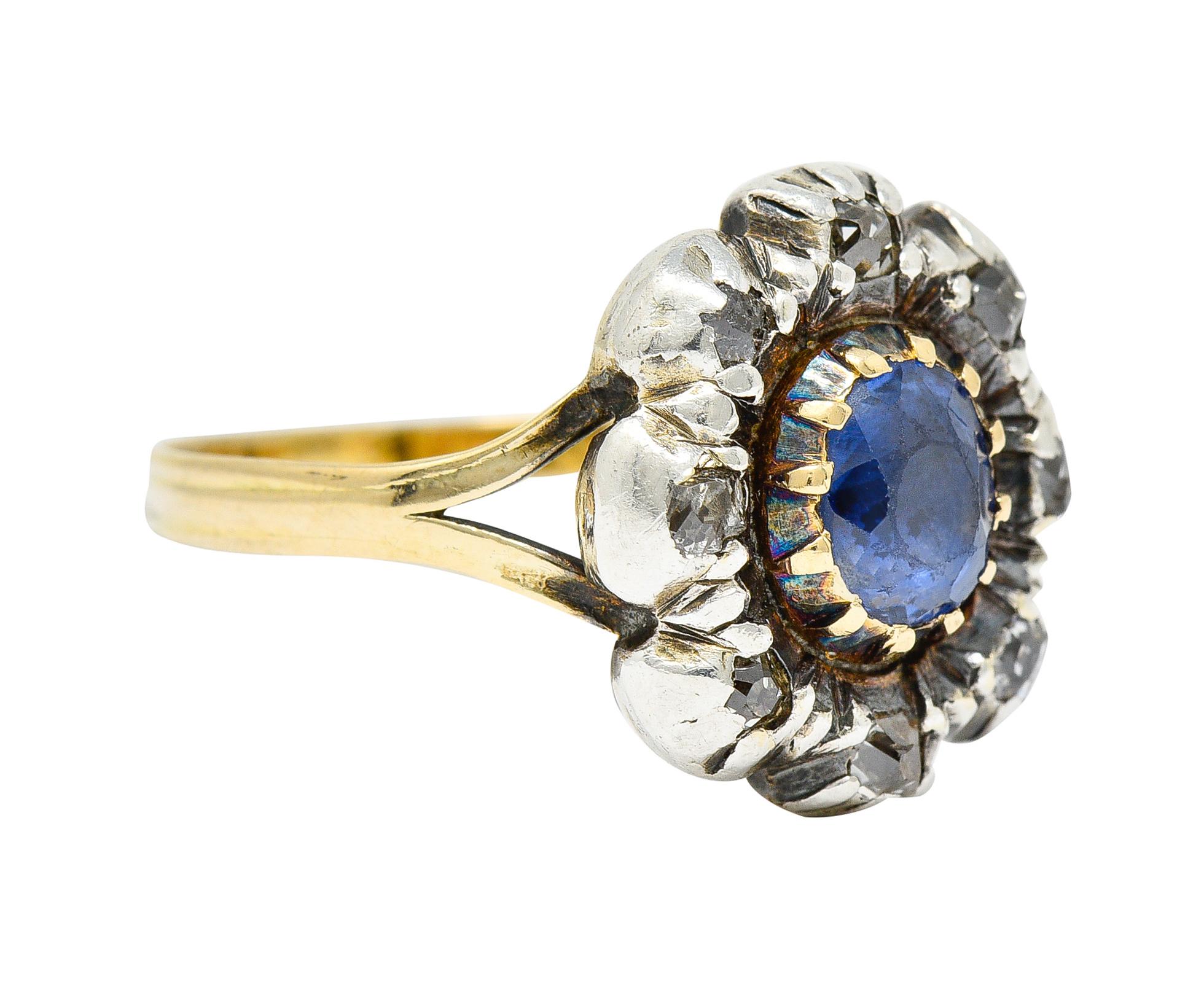 Floral cluster style ring centers an oval cut sapphire weighing approximately 0.90 carat

Set in gold with strongly violetish-blue color - foil backed

Surrounded by a halo of table cut diamonds weighing approximately 0.40 carat - set in
