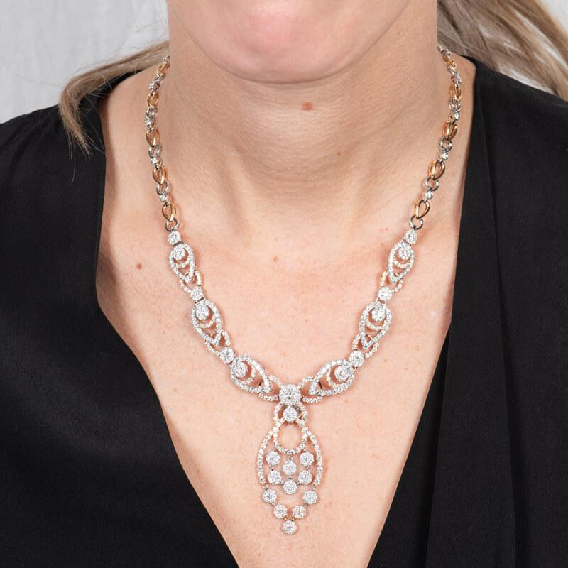 This beautiful, intricate, and one of a kind necklace features 18.00ct total weight in pave set round diamonds set in 18 karat white and rose gold. It is linked together in pear and circular shaped chains with a pendant drop. Box and double safety