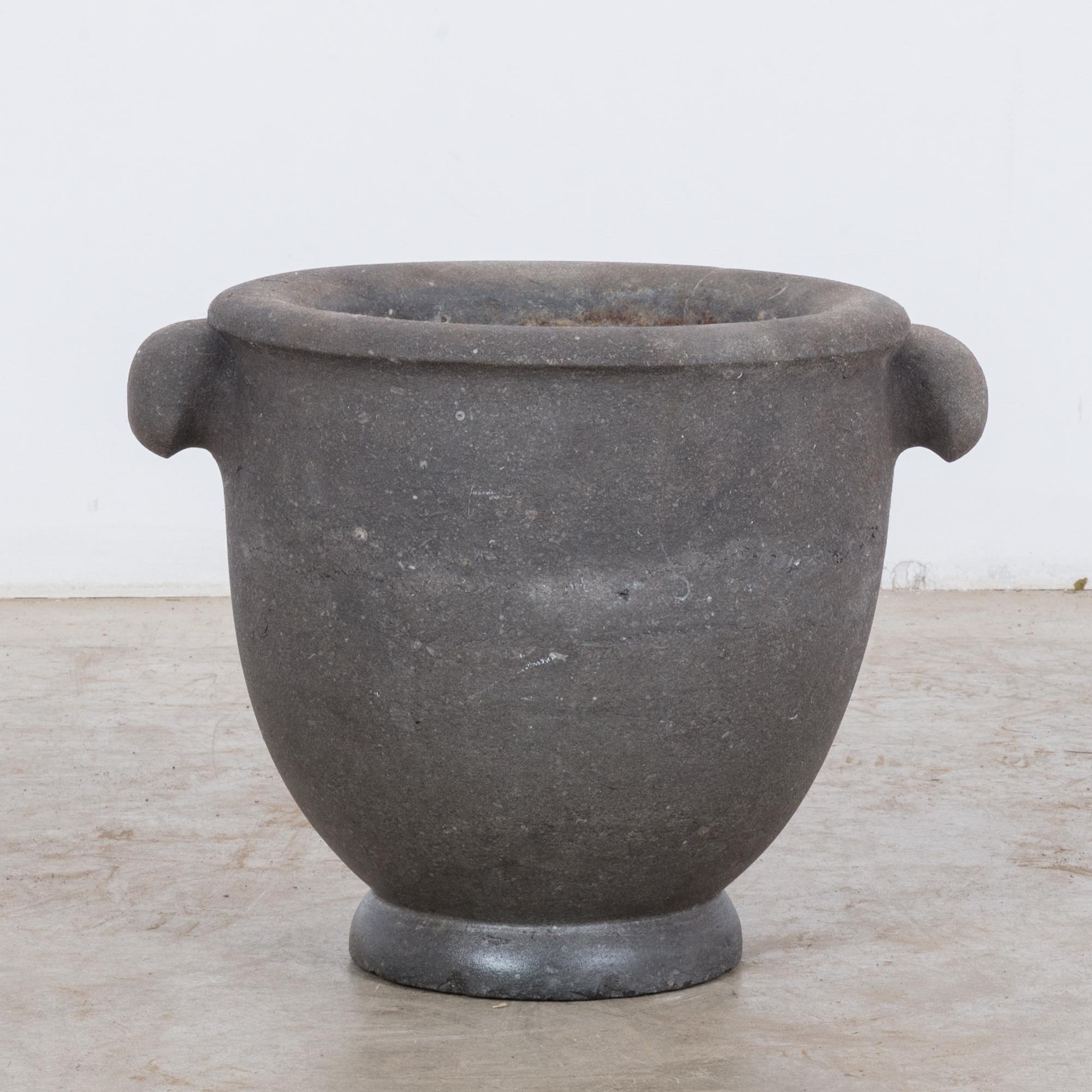 This large, black stone mortar was made in Belgium, circa 1800. It features a rolled rim and handles on the sides. A round foot gives the mortar a slight elevation. With its beautifully weathered patina, it will be a unique decorative piece for your