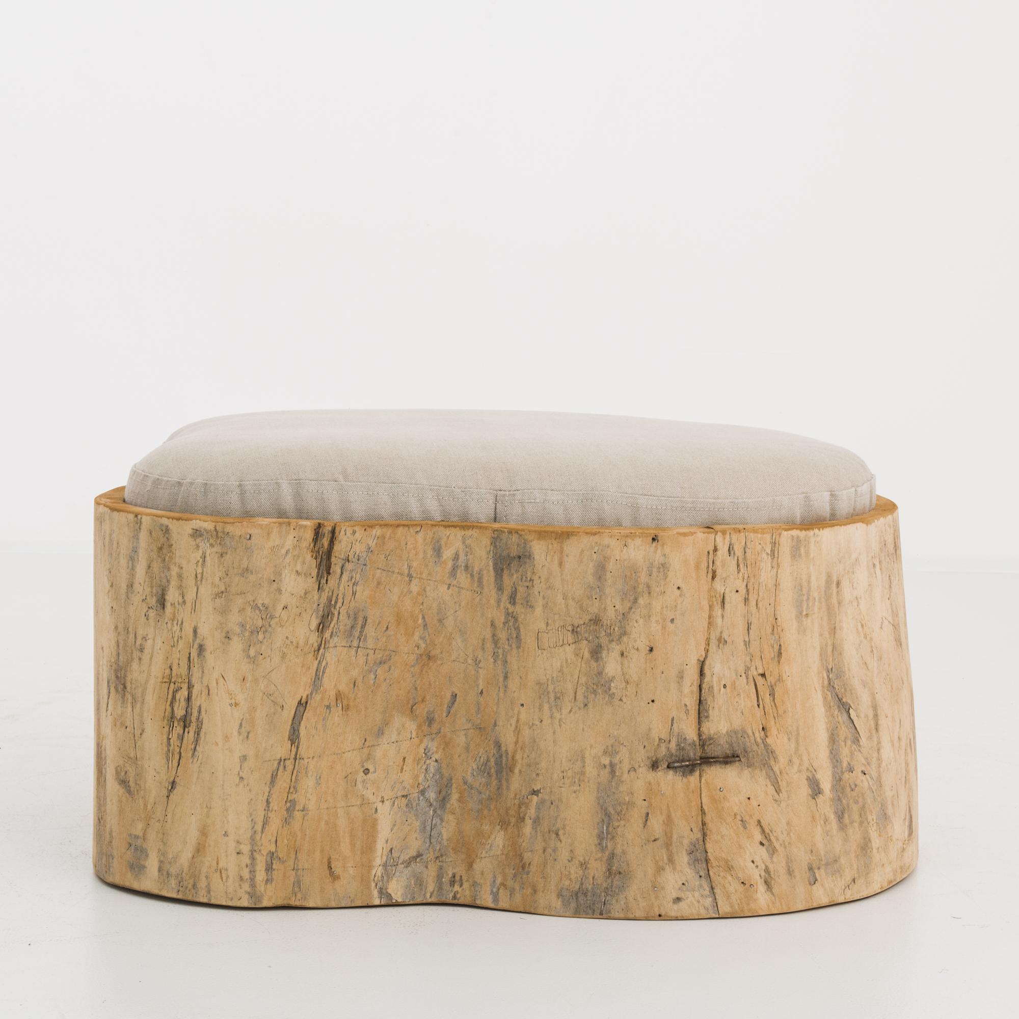 A hollowed tree trunk from Poland, circa 1800 fashioned into an elegant wooden pou. The natural contours of the stump create a unique shape, while the organic finish lends a rustic textural appeal. The cushion is upholstered in a taupe linen fabric,