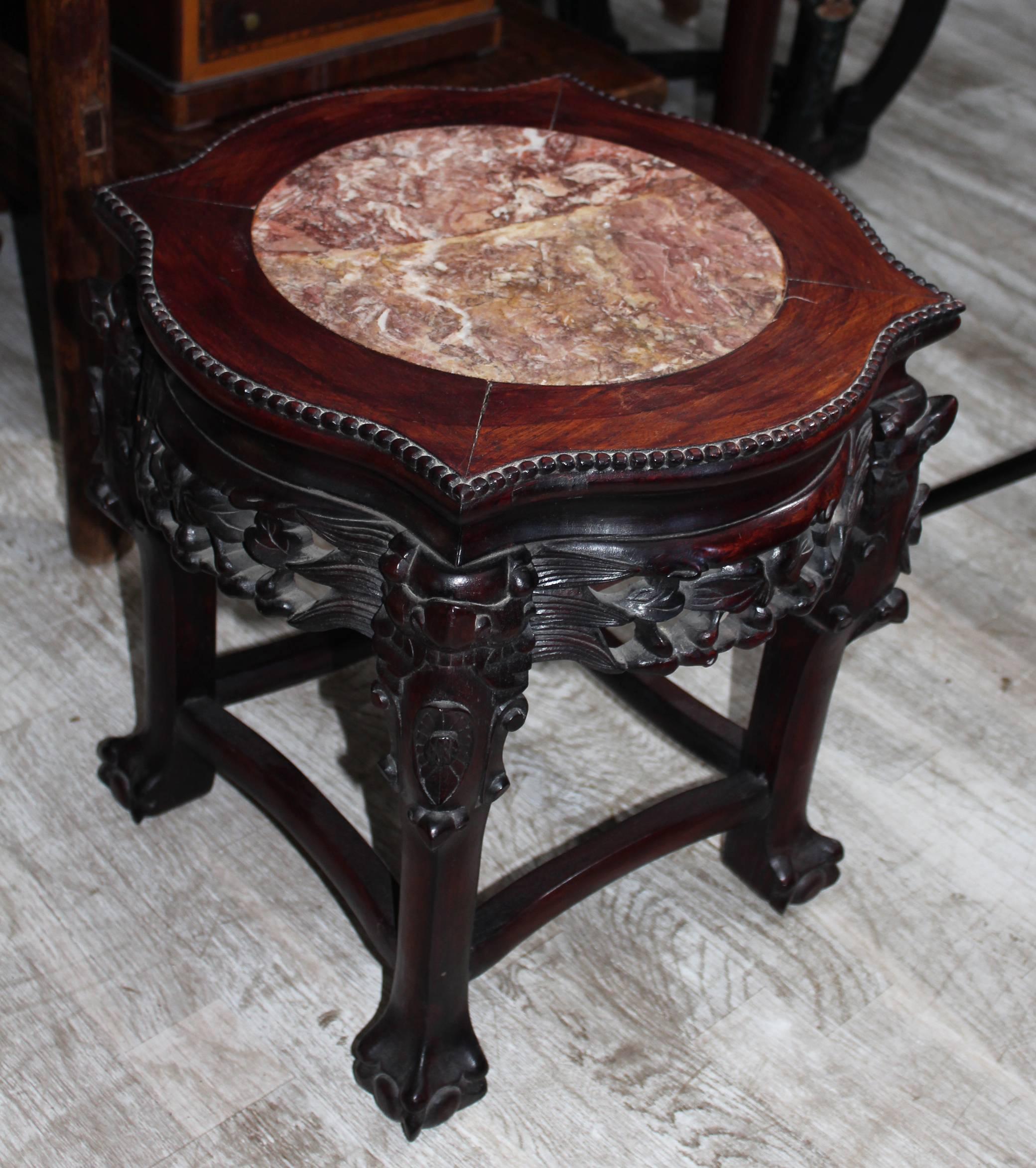 19th century Chinese wooden pedestal with stone top and elaborate hand-carved decorations, particularly the claw shaped legs.