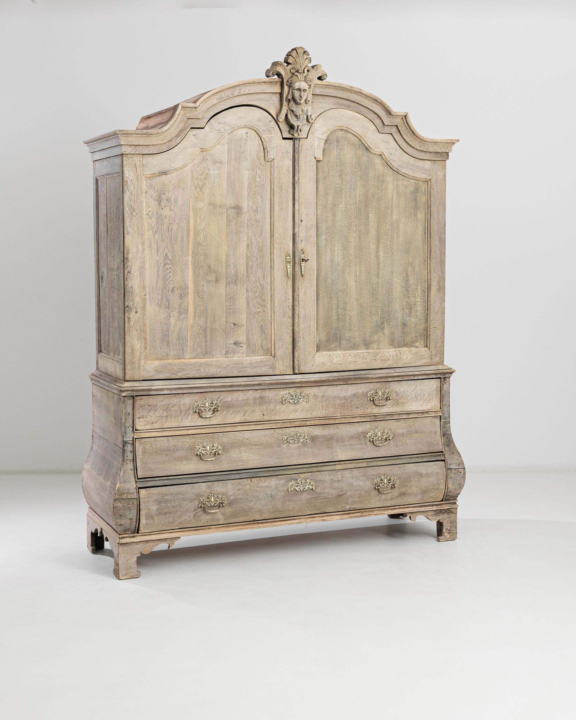 A bleached oak cabinet from the Netherlands, produced circa 1800. Standing nearly eight feet tall on cornered feet, this elegant cabinet impresses with its presence. Featuring a double door upper cabinet holding several shelves and sliding drawers,