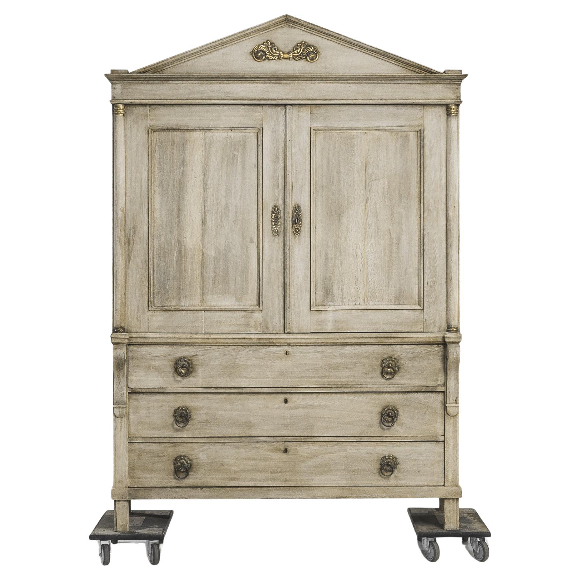Cette armoire hollandaise en chêne blanchi datant des années 1800 est un parfait exemple d'artisanat et de design intemporel. Le meuble est orné de somptueux accents dorés et possède deux portes principales qui s'ouvrent pour révéler deux étagères