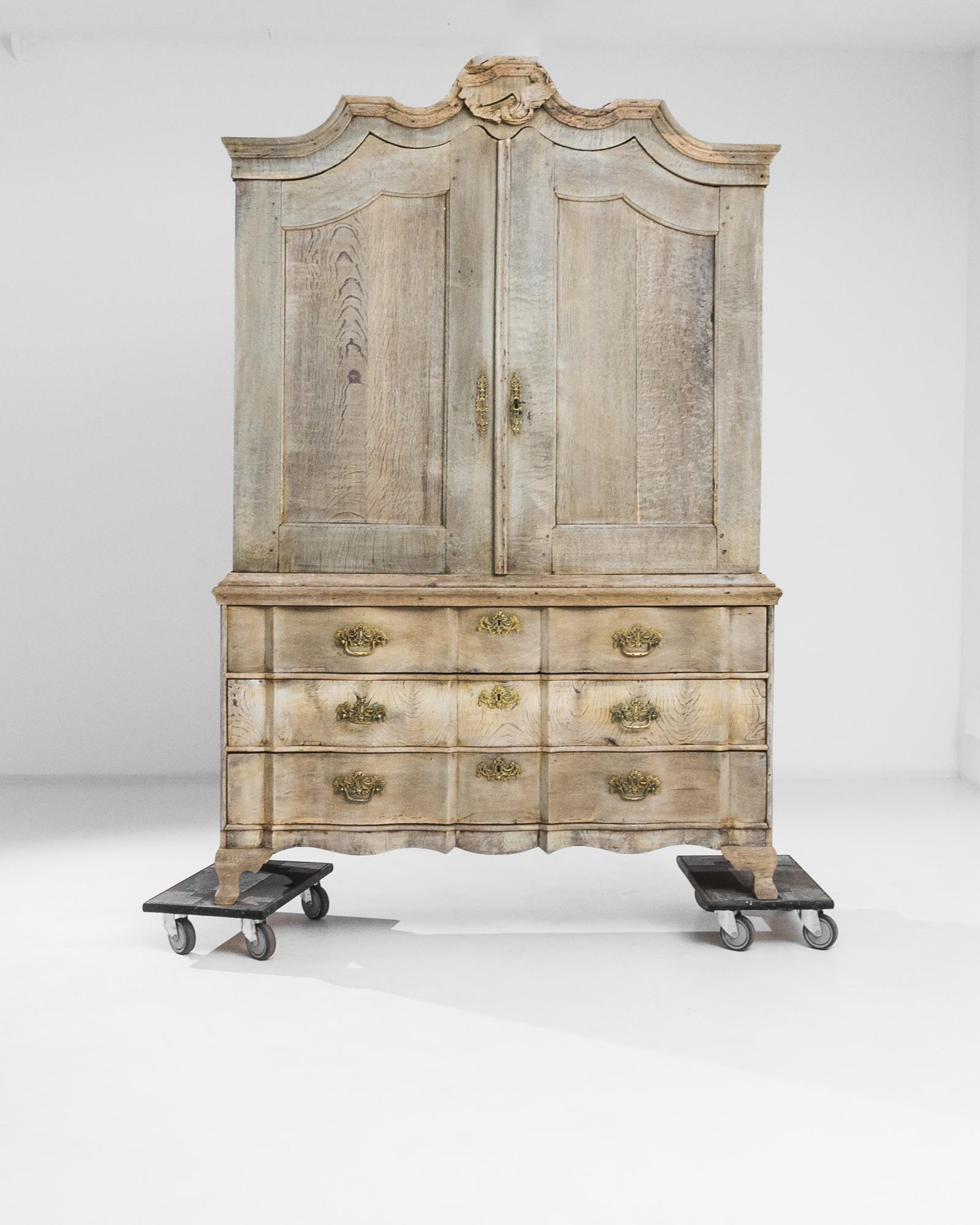Elevate your space with the timeless allure of this 1800s Dutch bleached oak cabinet, a true testament to exquisite craftsmanship and refined elegance. Standing tall, it boasts three sliding bottom drawers and a spacious top compartment adorned with