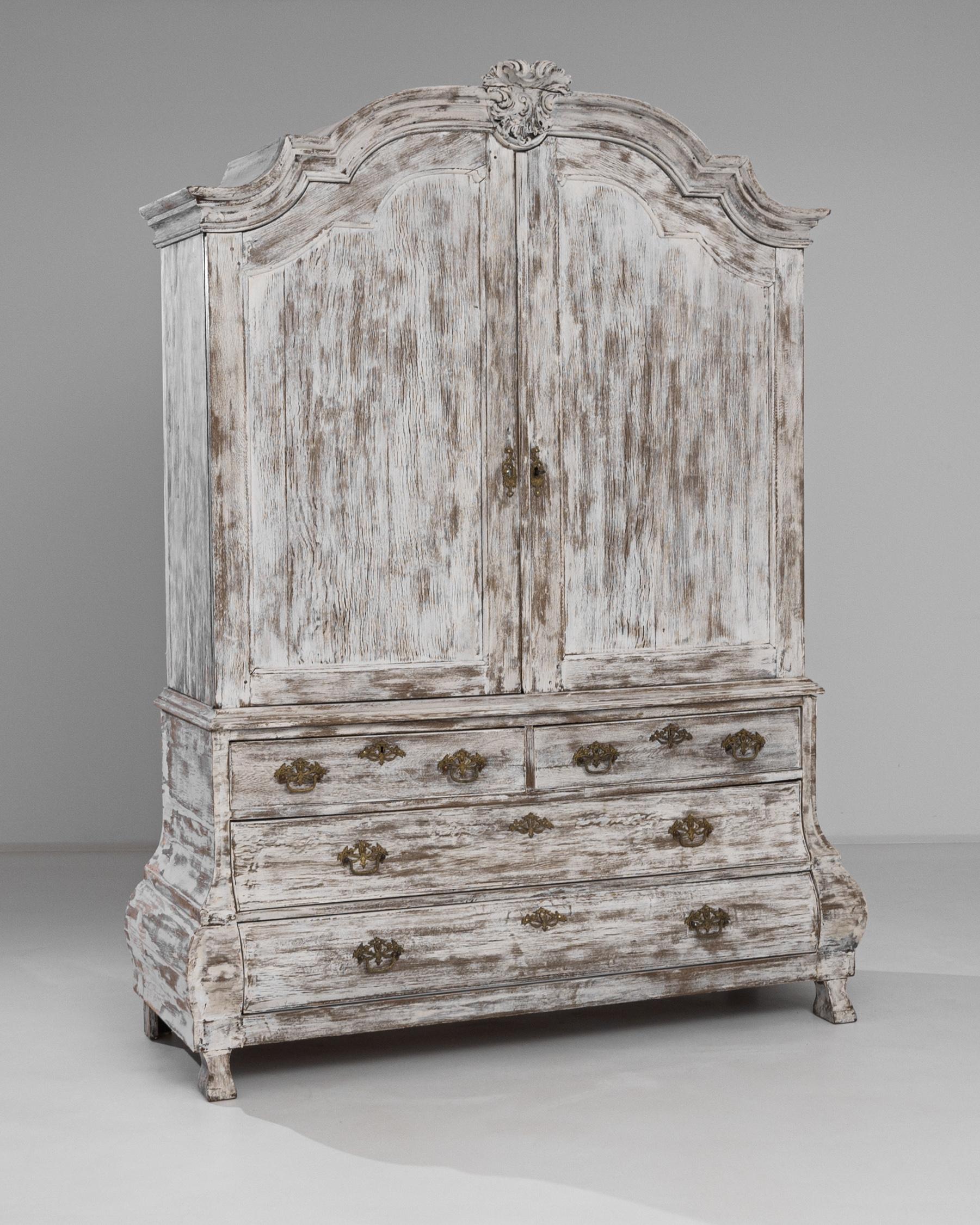 This stylish antique cabinet lends an air of grandeur to any space. Made in the Netherlands circa 1800, the broad case stands proudly atop curved feet. Elaborate moldings are crowned by a carved acanthus motif — a foliate design that has inspired