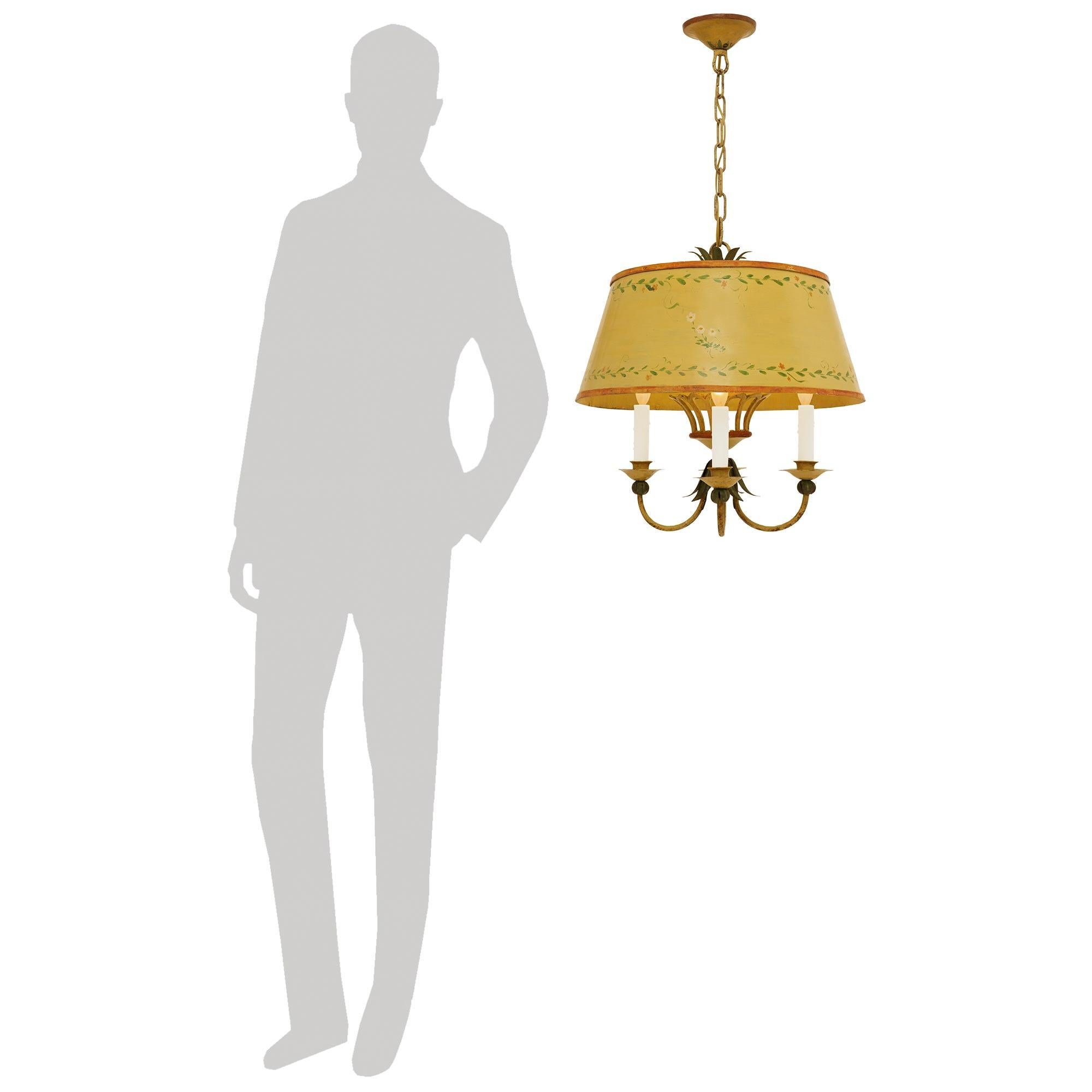 A charming and most decorative pair of French late 19th century Louis XVI st. patinated Iron and Tole chandeliers. Each most elegant four arm and four light chandelier is centered by a wonderful inverted floral reserve from where the four scrolled