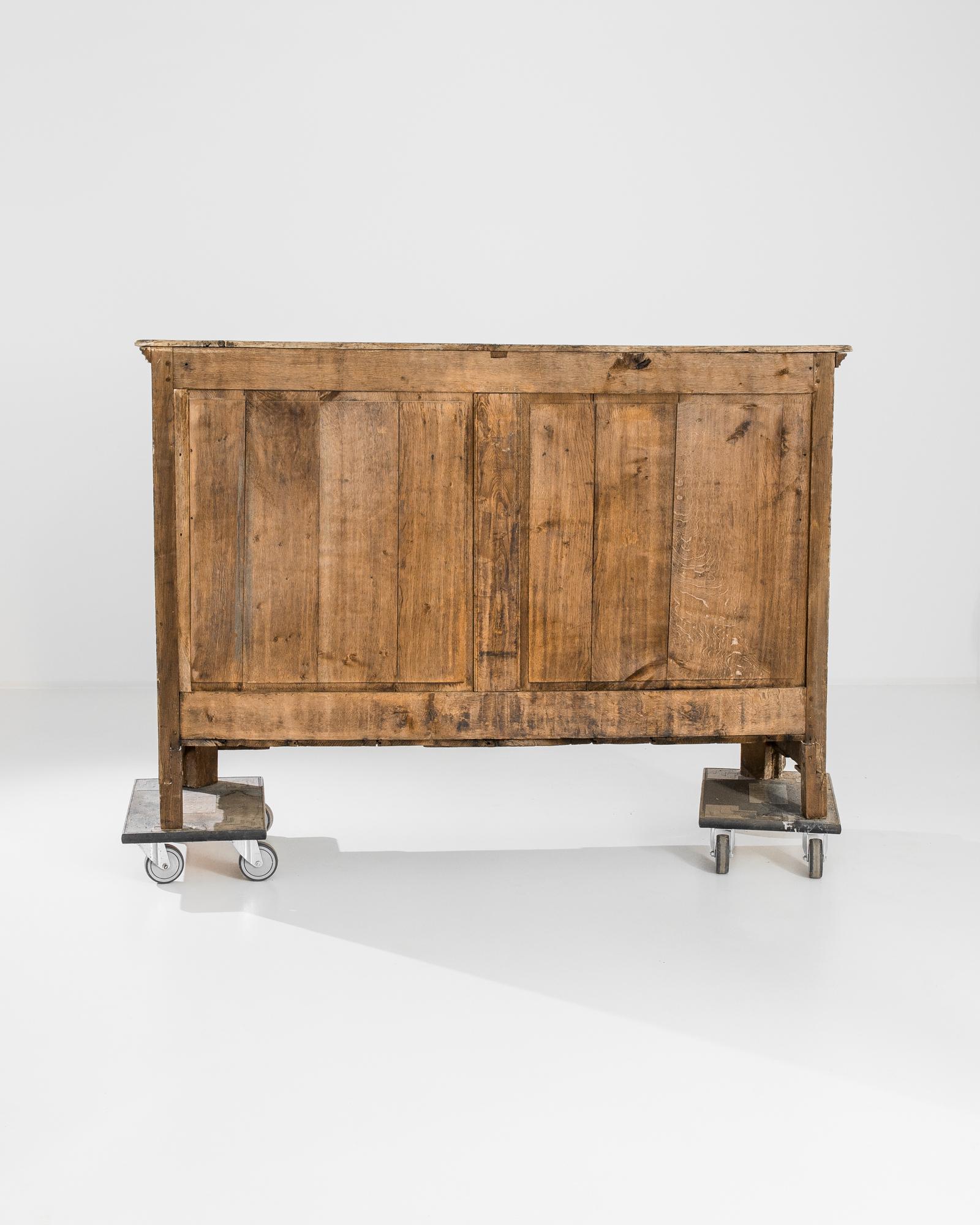 A bleached oak buffet from France, produced circa 1800. Birthed at the beginnings of the French Empire, this beautiful buffet features a trio of sliding drawers over a locking, double door cabinet with two shelves. Covered in delightful