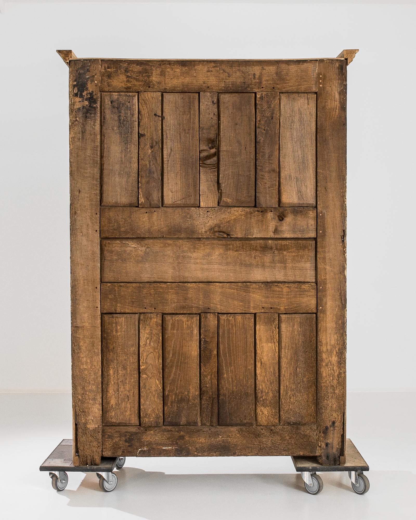 A bleached oak cabinet from France, produced circa 1800. An expertly crafted antique from the epoch that spawned the French empire, featuring a three shelf cabinet behind locking double doors. With a cornice like the wings of an omega, this stately