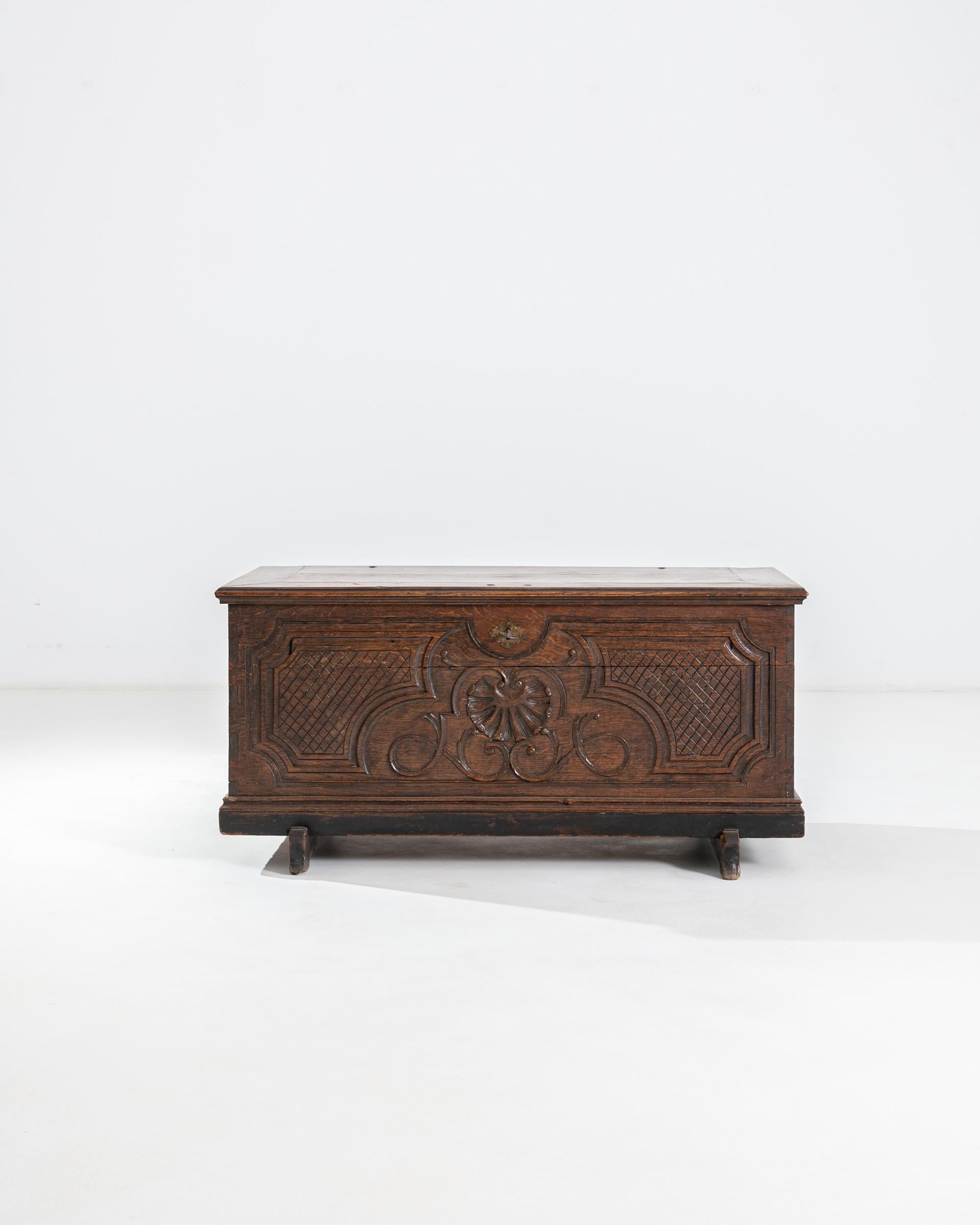 An early 19th century carved trunk produced in France, this large trunk on a stand is a sculpted delicacy. Sporting an adroitly carved front, the ornate case exhibits a natural lush patina of auburn tones with darker accents. A central shell and