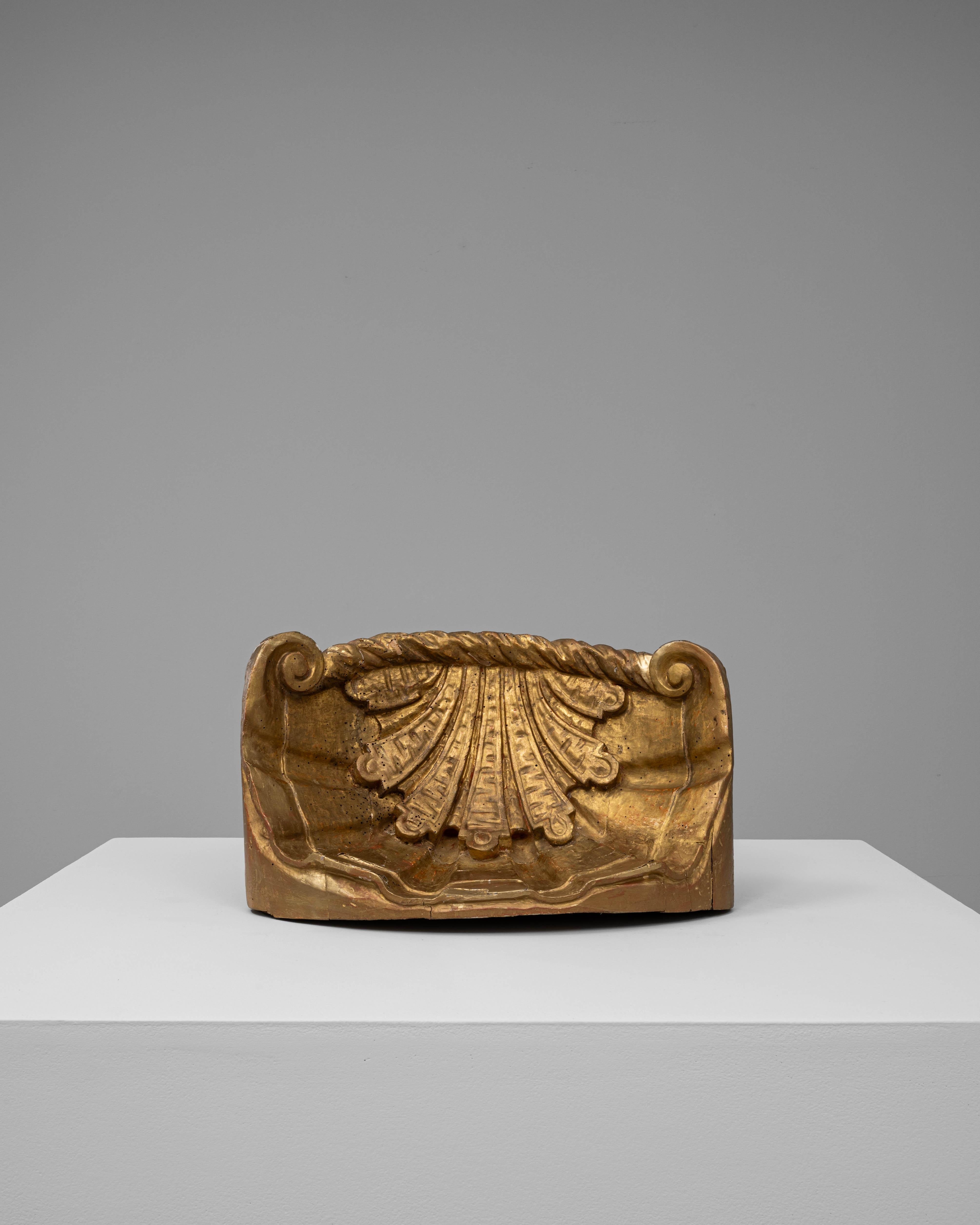 Questo ornamento in legno dorato francese del 1800 è un frammento riccamente intagliato che riflette l'eleganza e la raffinatezza decorativa della fine del XVIII e dell'inizio del XIX secolo. Con la sua forma slanciata e l'ornamento di foglie