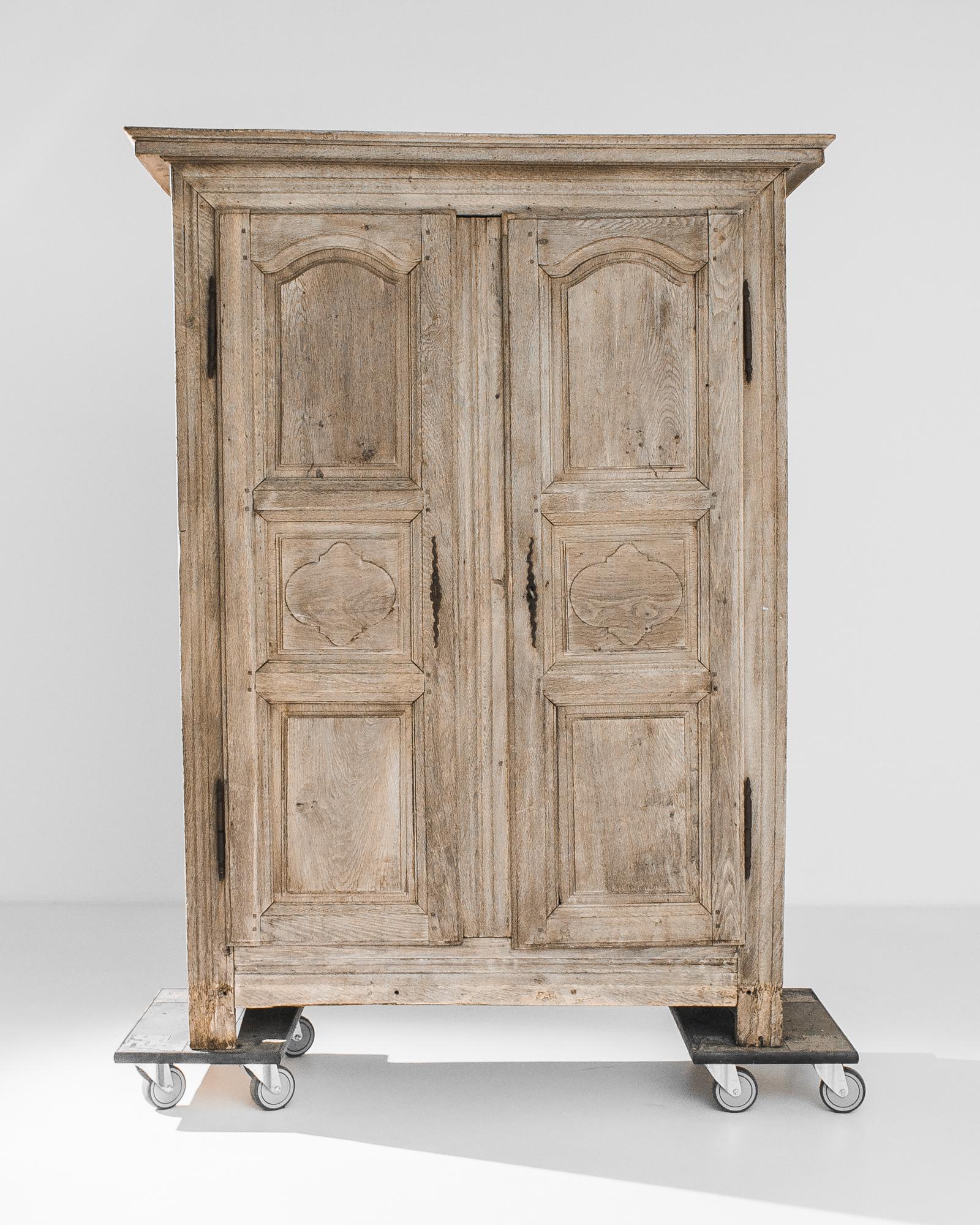 An oak cabinet from France, circa 1800. Carved quatrefoil motifs decorating the central panels of the doors and cast iron hinges lend a subtle gothic inflection to the broad silhouette. The pale golden tone of the restored oak provides a delicate