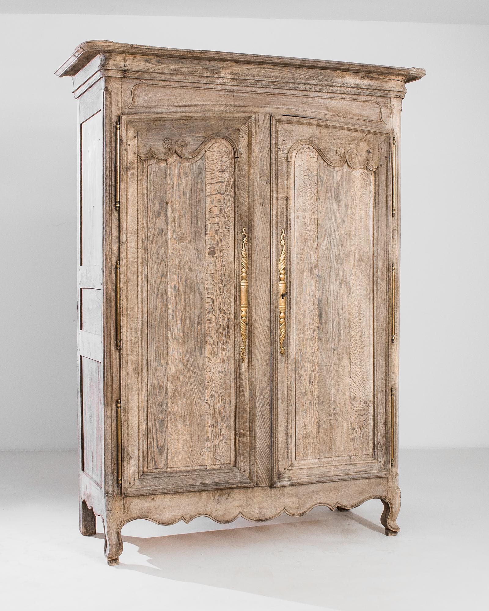 Romantic paneling and the subtle tone of the restored wood make this antique cabinet a Baroque beauty. Made in France in 1800, the fluid arches and leafy scrolls of the door panels are echoed in the the scalloped apron and graceful cabriole of the