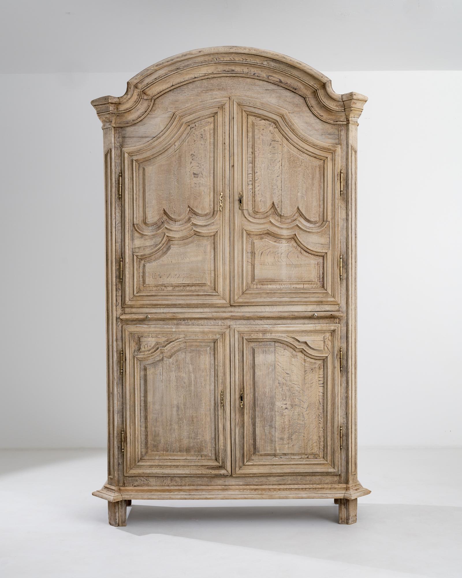 This antique oak cabinet combines Baroque theatricality with the simple beauty of Provincial craftsmanship. Built in France circa 1800, the dramatic arch of the cornice provides a striking frame for the beautifully paneled doors. The contours of the