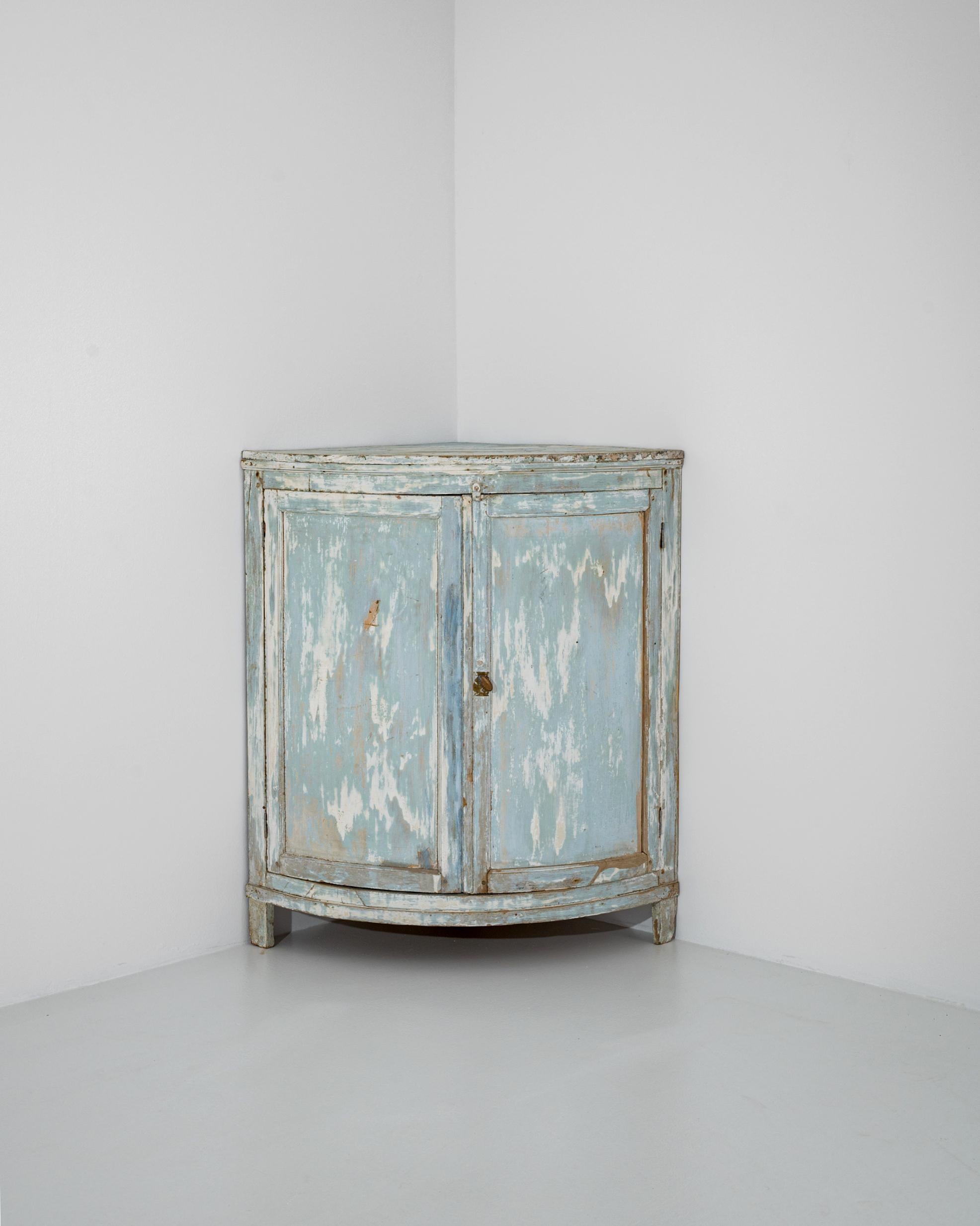 A clean, curving form and a baby blue patina gives this antique wooden cabinet an air of country simplicity. Made in France in the 1800s, the cabinet is built to fit perfectly into the corner of a room —an astute way of making use of space that
