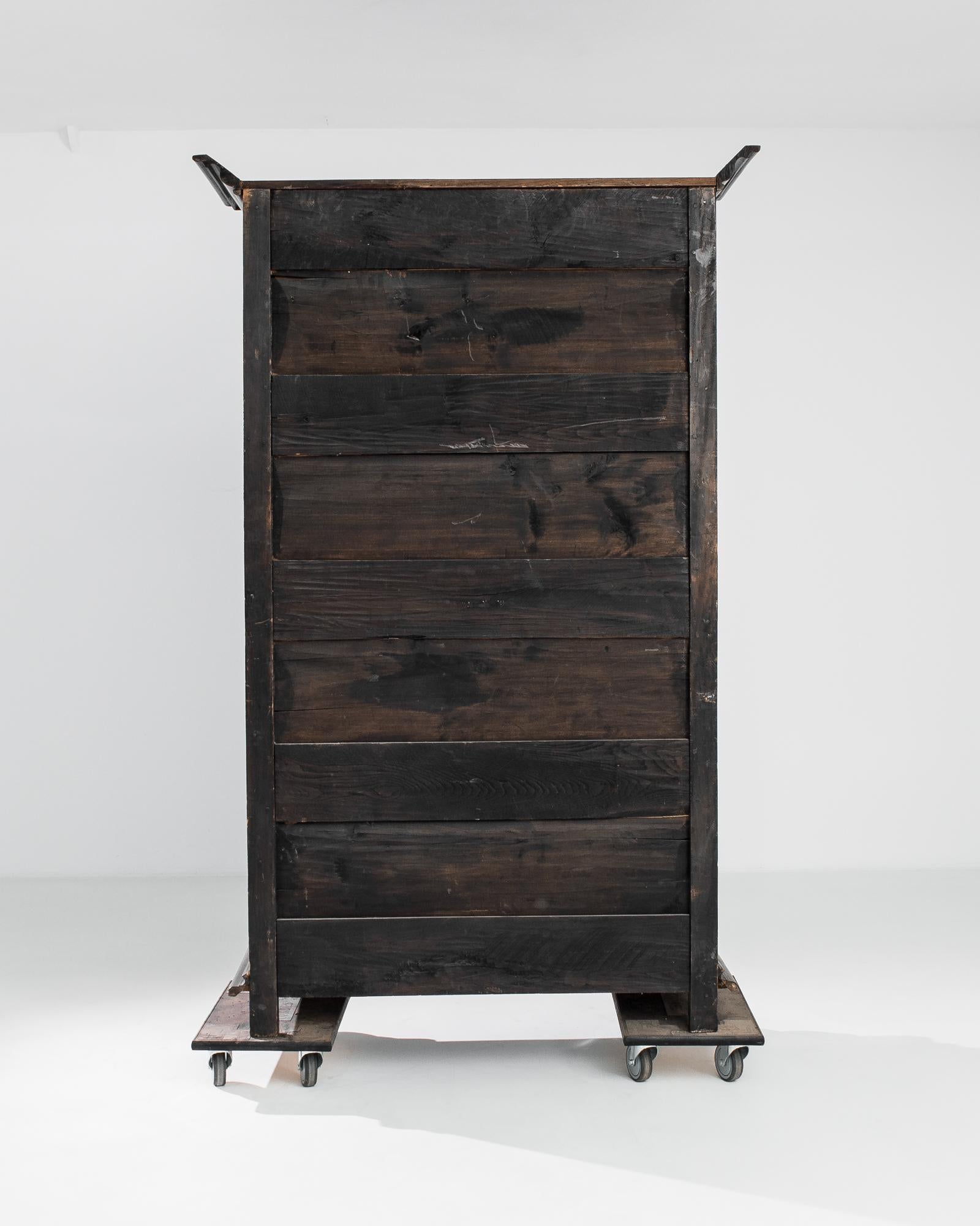A hardwood cabinet with original patina from France, produced circa 1800. Standing over seven feet tall, this stately chest features two levels of locking, two-shelf cabinets separated by a row of two sliding drawers. The richly decorated facade is