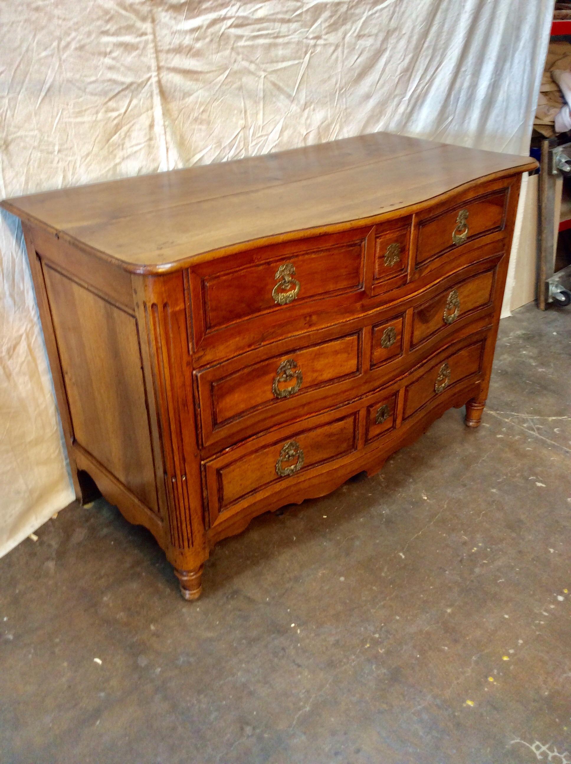 Found in the South of France, this 18th century French Chest of Drawers is constructed of solid walnut having a serpentine front with conforming top, drawers and apron rest on hand carved feet. Each of the four drawers with dovetail joinery feature