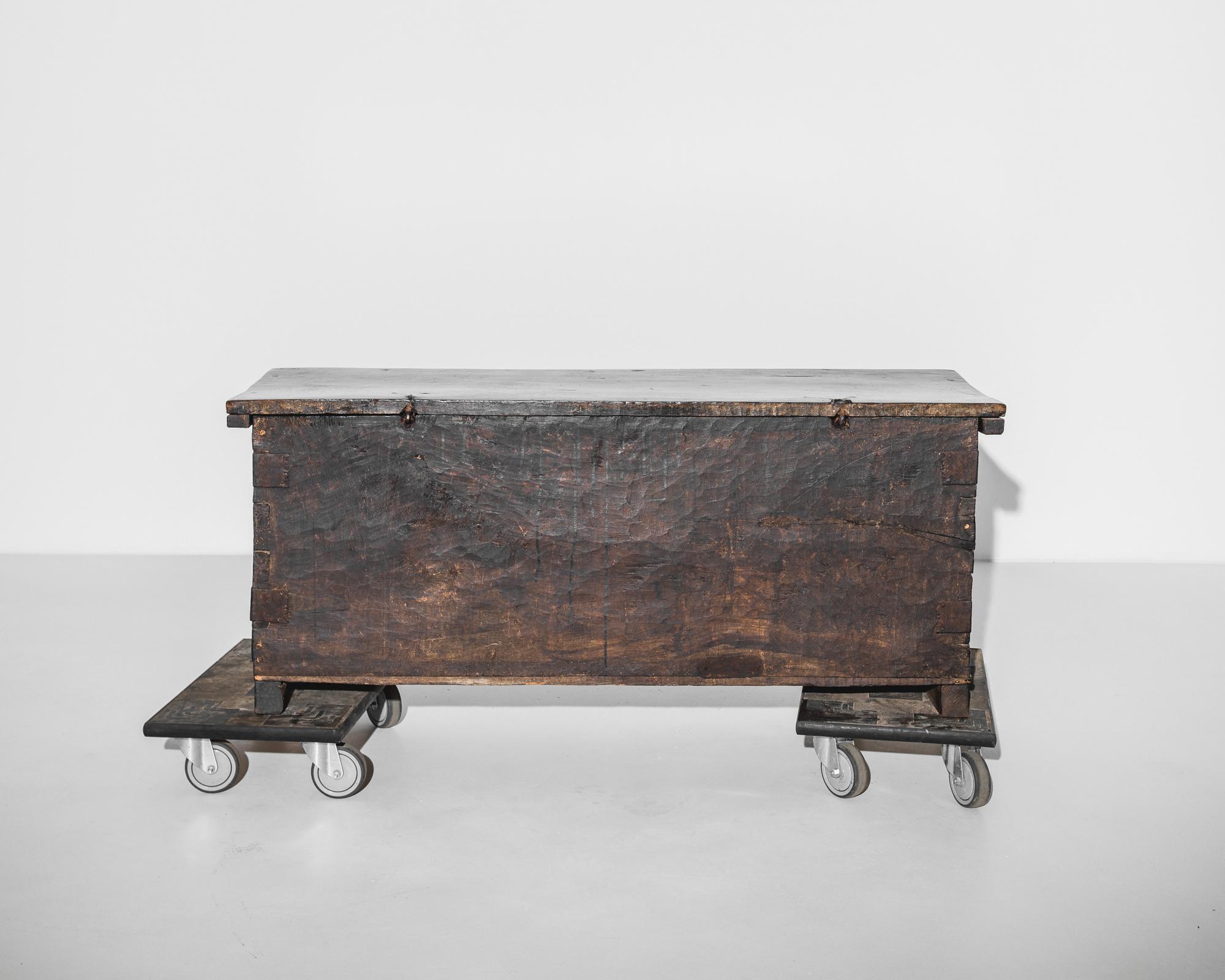 A wooden trunk from France, circa 1800, built in Neo-renaissance style. A crenellated apron and the deep, enigmatic color of the original patina lends a gothic inflection. The rough-hewn texture of the chest creates textural appeal, while the