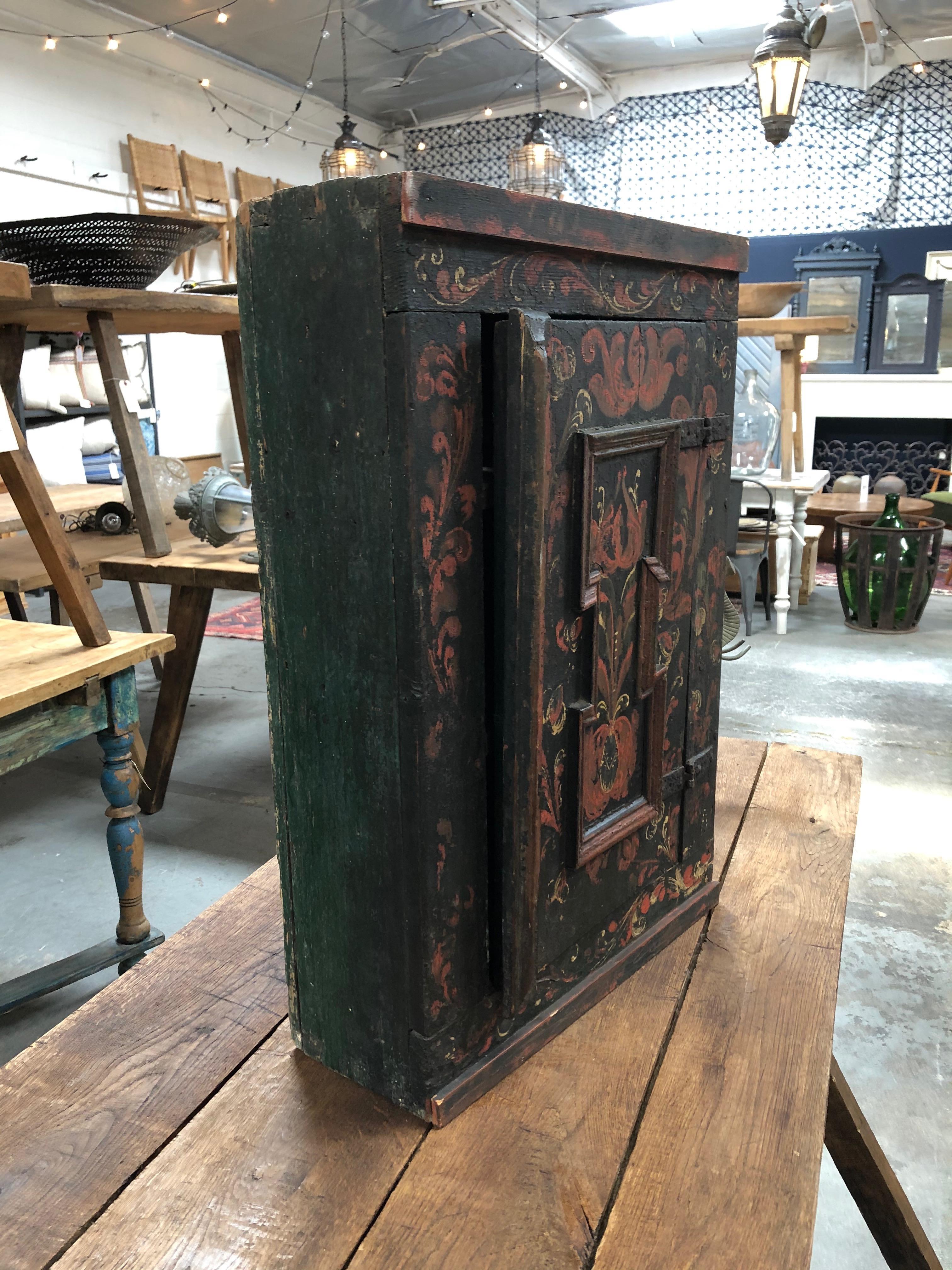 This wall cabinet from the 1800s is hand painted in a beautiful red and black color scheme. A great decorative piece that is also functional, it adds a timeless elegance to any space.