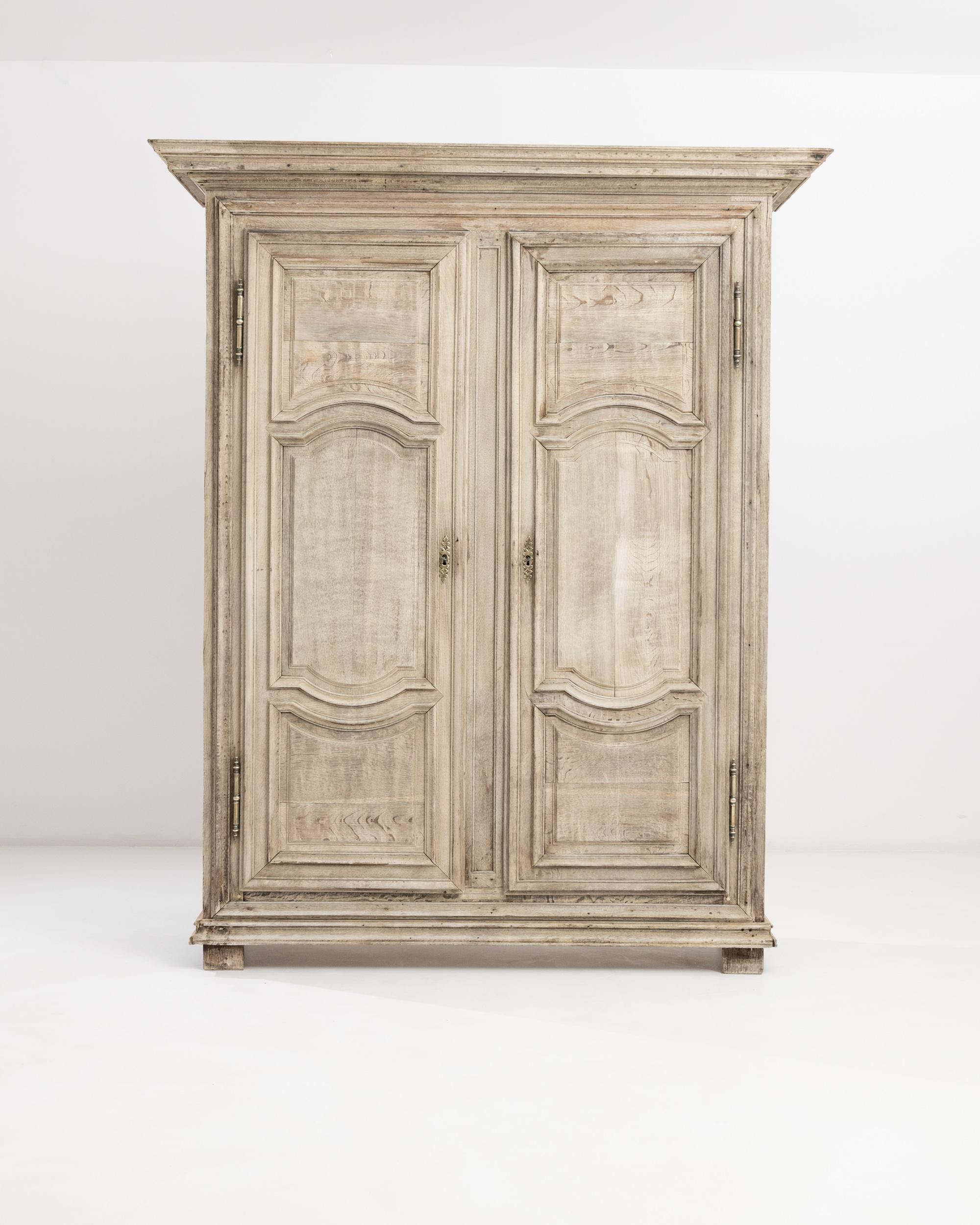 Grand proportions and beautiful panelling make this antique oak armoire a magnificent find. Made in France circa 1800 in the style of Louis XIV, the quality of the cabinetwork is visible in the deep relief of the contoured moldings and the graceful