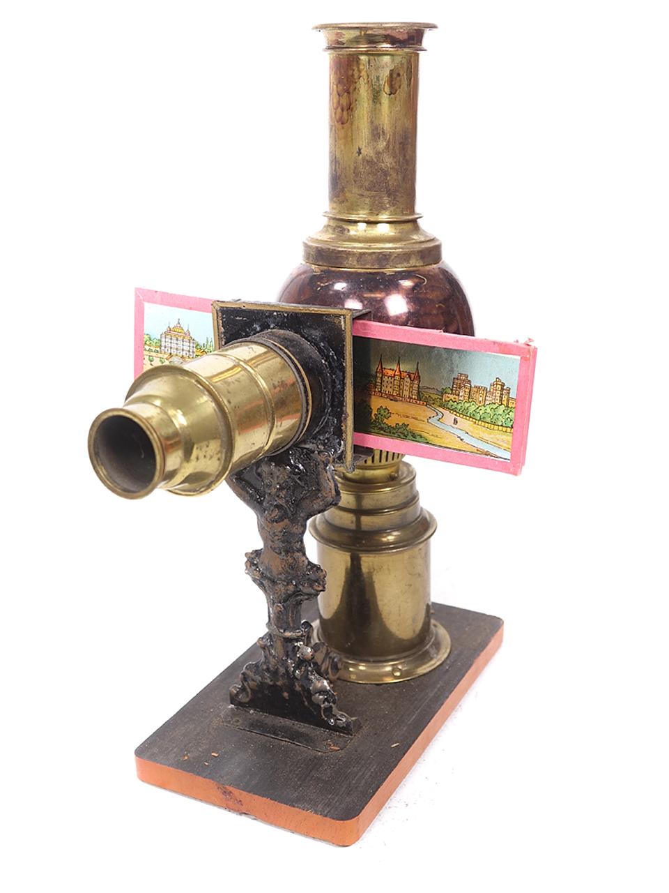 This is a beautiful and decorative 1800 magic lantern full boxed set. We believe it was created by Ernst Plank. The body has unusual sphere brass kerosene lamp housing and a figural character holding the lens. It's complete and even comes with a