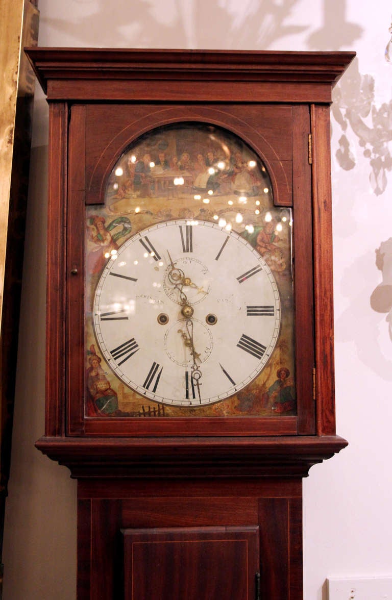 This is a working Scottish grandfather clock from the 1800s with chimes. It has a hand painted metal face and ornate hands. There is a second hand clock at the top, and a separate one at the bottom (for the days of the month perhaps). On the face it
