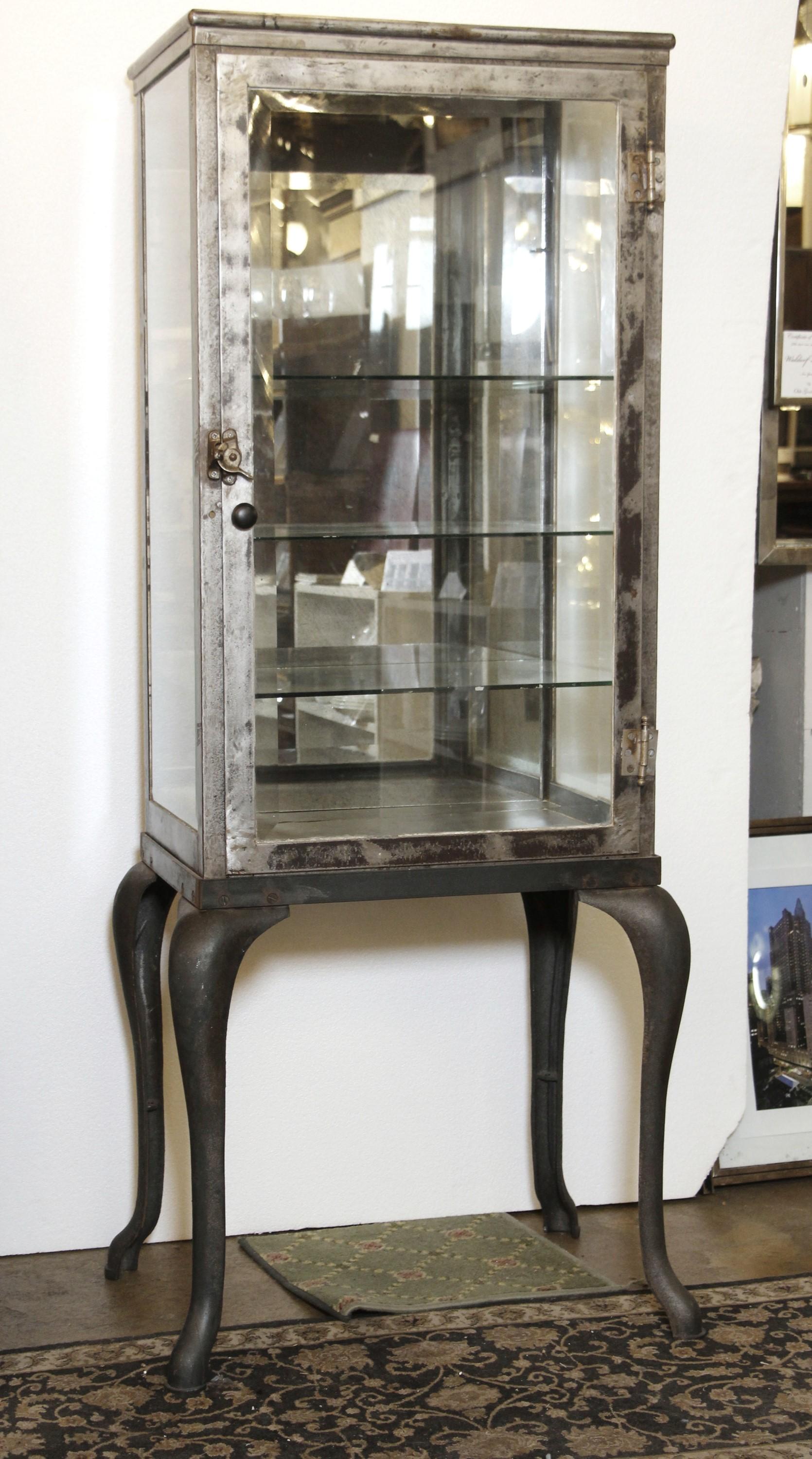 Late 1800s dental or medical cabinet featuring cast iron cabriole legs. Top cabinet is made out of steel. Interior is set up for four shelves. Now stripped and lacquered with a new mirror installed in the back. Please note, this item is located in