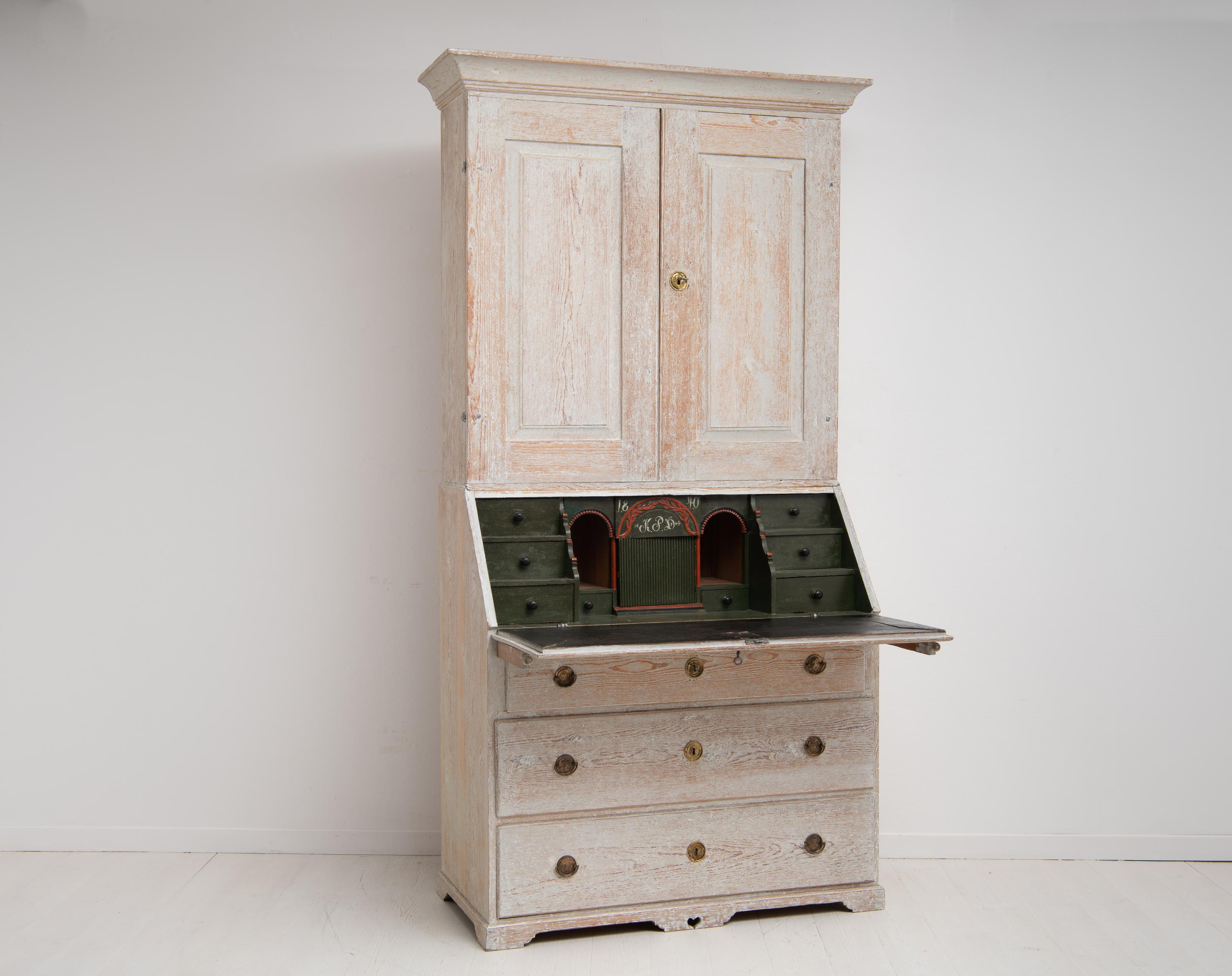 Swedish Gustavian bureau cabinet made in pine from the 1800s. This country cabinet is from northern Sweden and made in two parts. The upper cabinet has doors with interior shelves and the lower cabinet has a writing desk and drawers. The interior