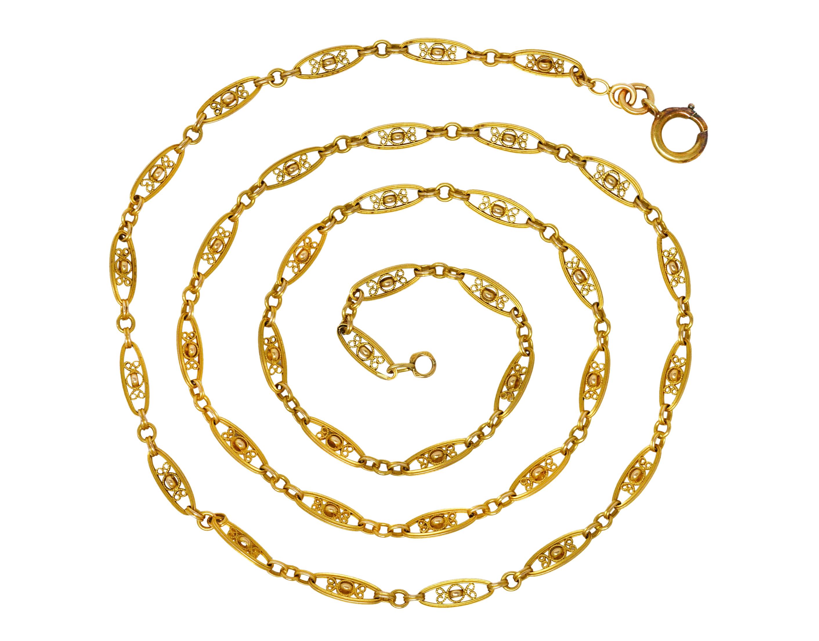 Chain is comprised of navette shaped links centering gold rings with curling filigree surround. Alternating with ridged oval and round links. Completed by spring clasp closure. Tested with French assay marks for 18 karat gold. With maker's mark.