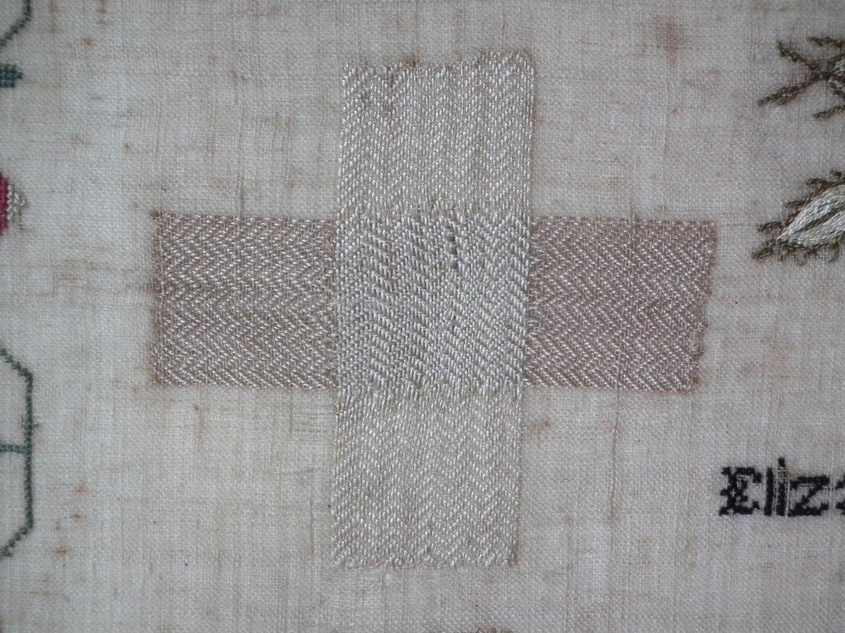 1803 Darning sampler by Elizabeth Clark. The sampler is worked in silk on linen ground, in a variety of stitches. Meandering strawberry border. Colors gold, cream, pale blue, black, red and green. Signed and dated 'ELIZABETH CLARK Apr 25 1803'.