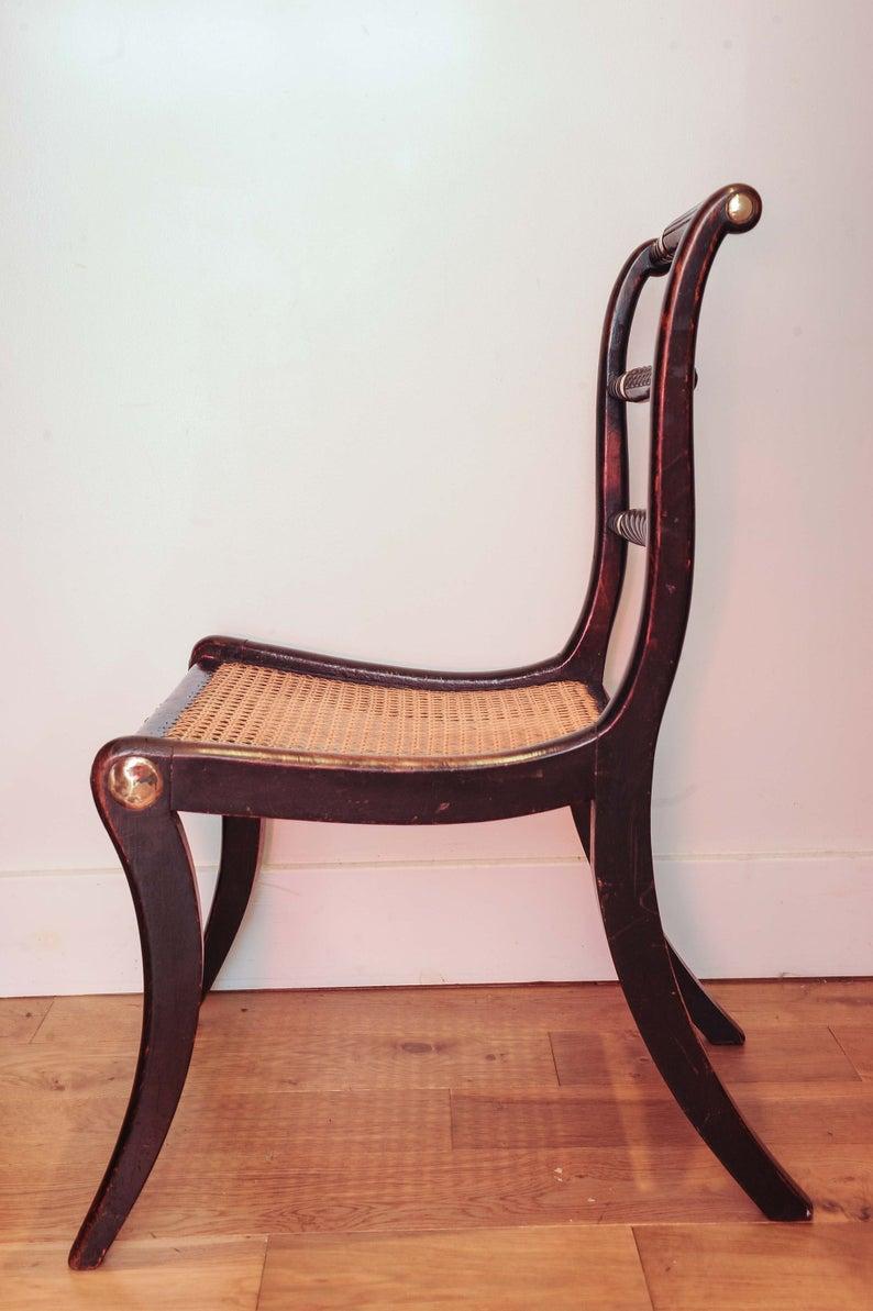 A fine quality early 1800s period ebonized beech “Trafalgar” chair with a triple rope-back, cane seat with brass collars and raised on sabred legs. This model of chair with the ropes and sabres symbolising naval power was ordered by Admiral Nelson