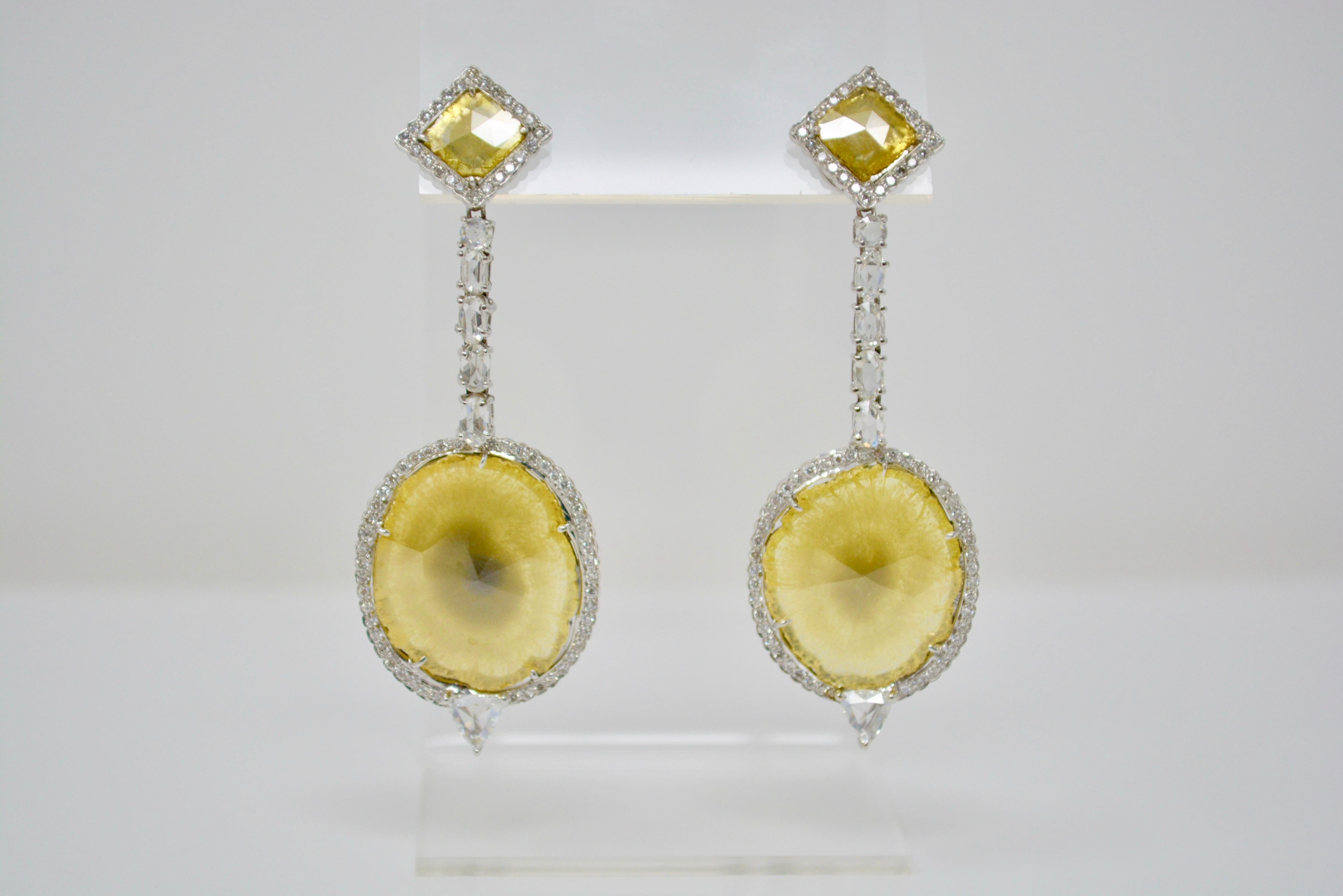 These magnificent and classy pair of natural yellow slice diamond earrings are set with a total of 13.09 carat of natural yellow slice diamonds and 5 carat of natural white diamonds with VS clarity. These are beautifully designed in 18k white gold.