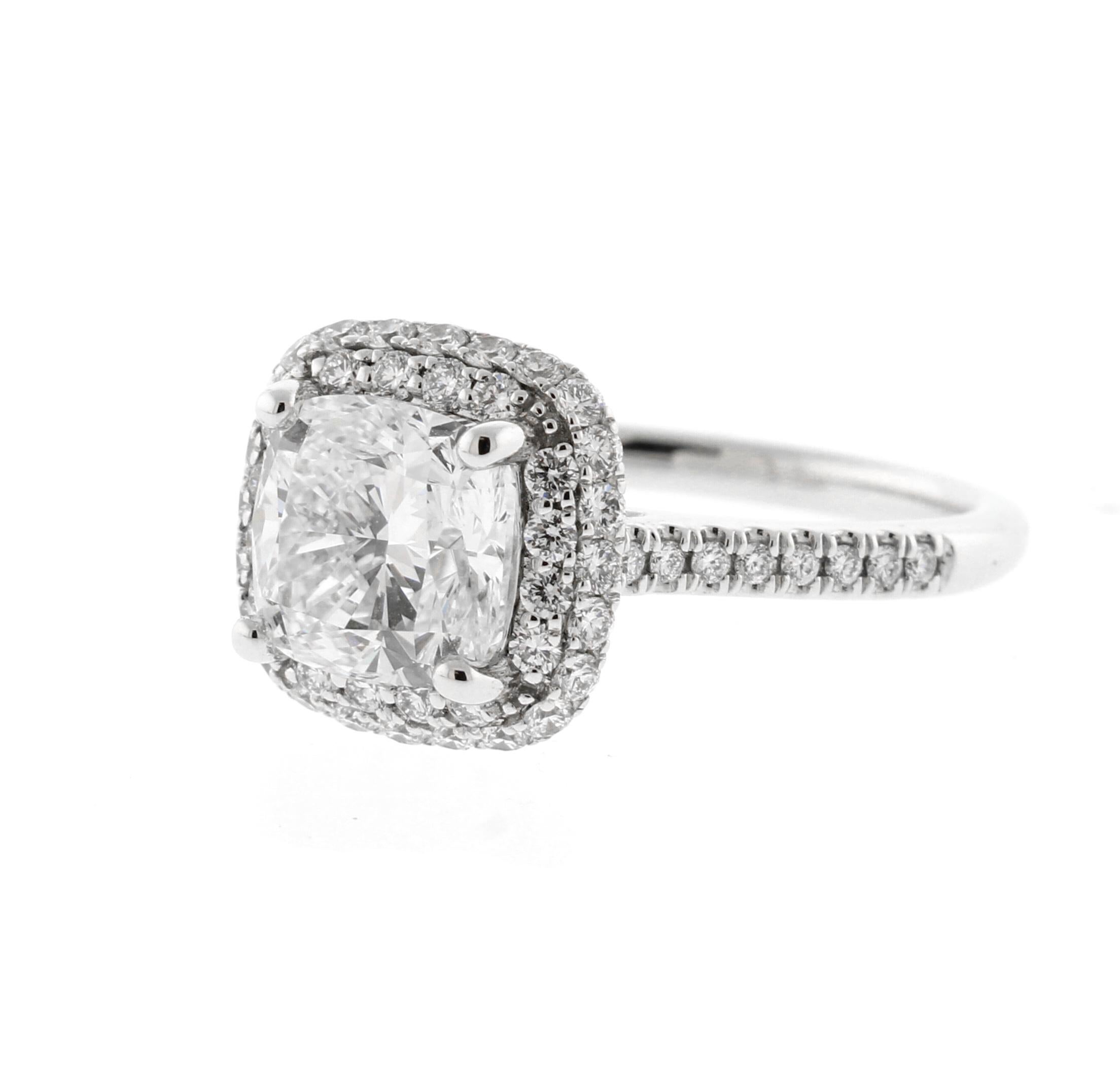 Lo squisito anello aureola mette in mostra un magnifico diamante taglio cuscino da 1,80 carati di eccezionale brillantezza. Certificata dalla GIA con l'ambito colore H e la purezza VVS2, la pietra centrale irradia fuoco e scintille da ogni
