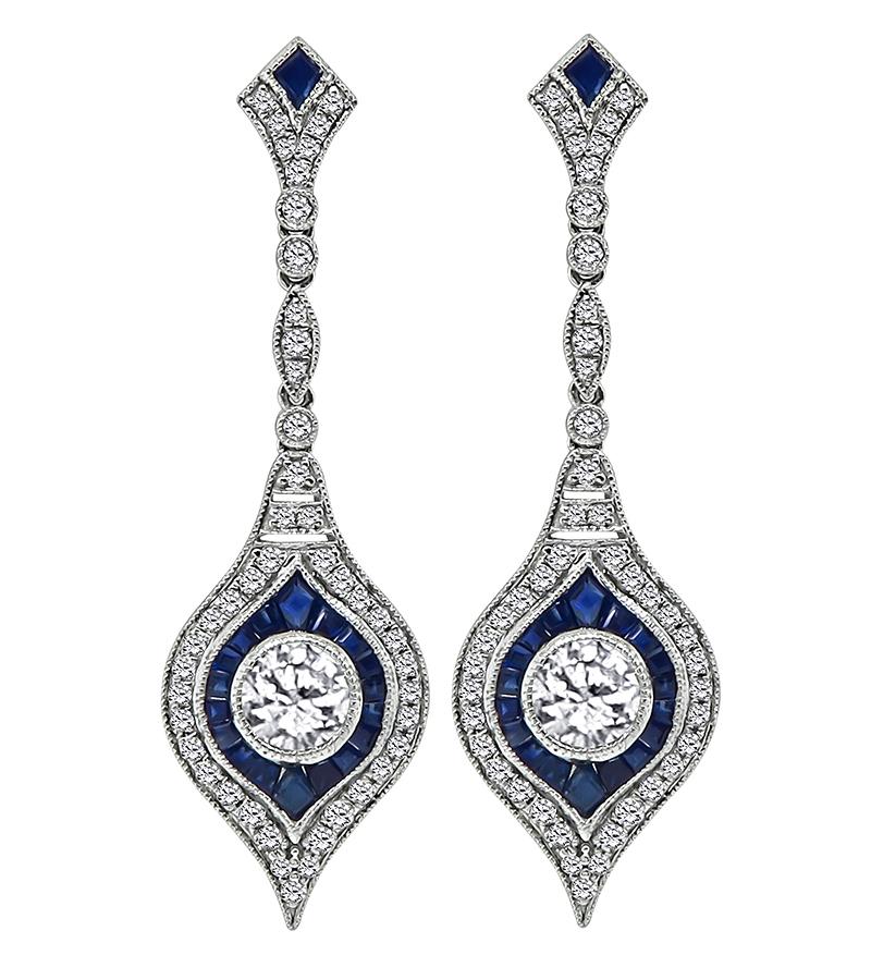 This is a charming pair of platinum dangling earrings. The earrings feature 2 large sparkling round cut diamonds that weigh approximately 1.00ct. The color of the diamonds is H with VS clarity. The large diamonds are accentuated by round cut