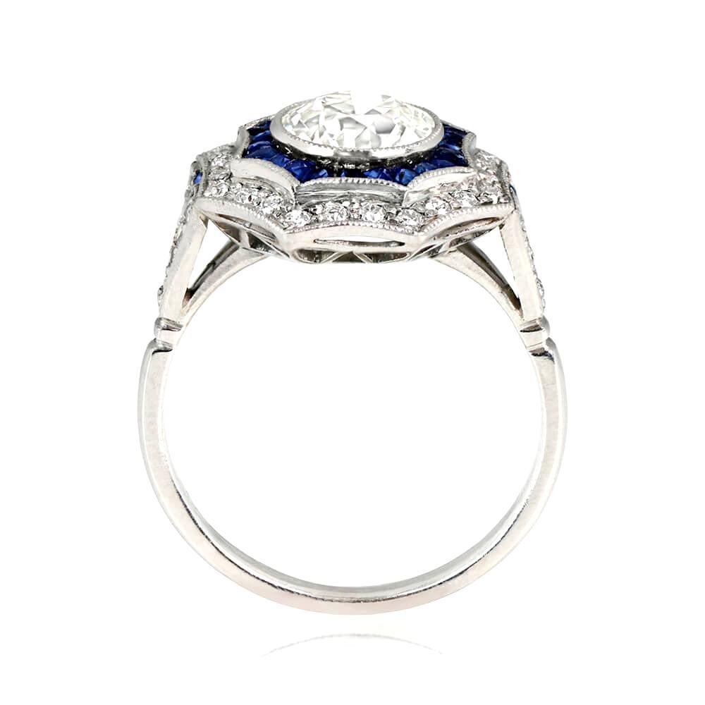 A platinum geometric engagement ring with a 1.80-carat bezel-set old European cut diamond at the center. The diamond is surrounded by a halo of French cut natural sapphires and a second halo of old European cut diamonds. The ring also features a