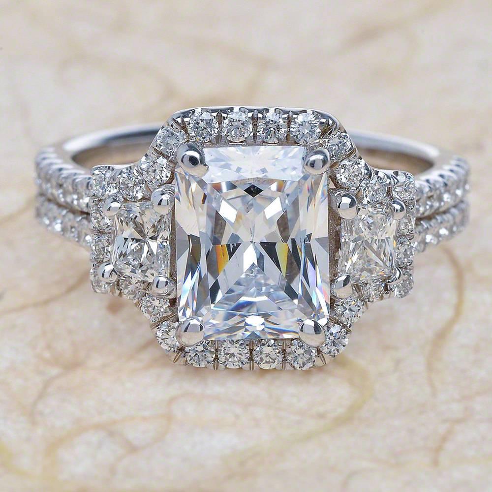 - Center Stone: Radiant Cut Moissanite 8x6mm (1.80ct)
- Side Stones: Round & Trapezoid Cut Diamonds 1.20ctw / Graded G SI1
- Metal: 14K White Gold

This piece is made-to-order. Please allow up to 7 Business Days to accomplish.