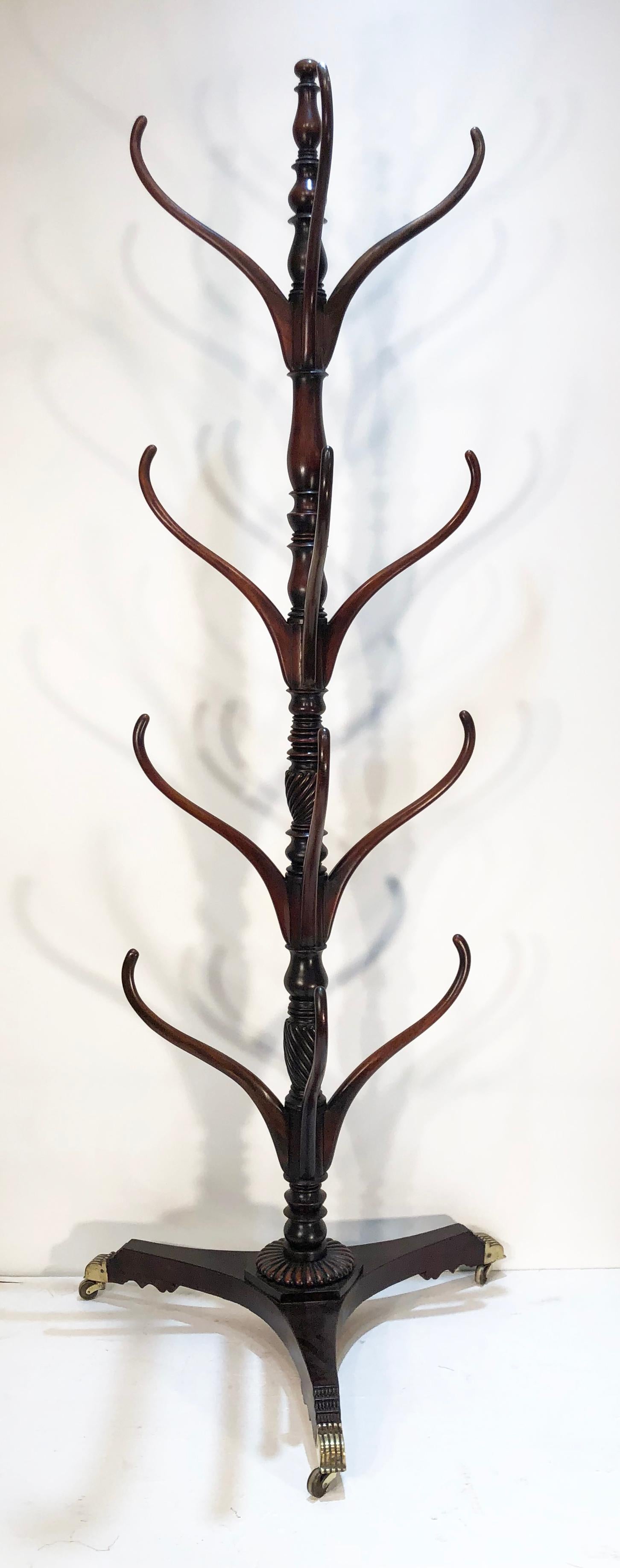 This beautiful high style West Indies Regency hat rack is rare because it is made to fit flat to the wall. This Jamaican/Barbados hat rack is of the highest British Colonial style. Incredible reeded brass casters mirroring the stepped down rings on