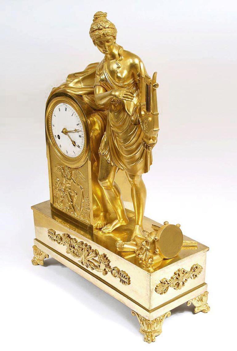 1810 Empire period clock made of gilded bronze
A clock from the Empire period on a rectangular base, supported on four winged lion's legs. On the basis of three sides applications. From the front it shows musical instruments and a cornucopia. In