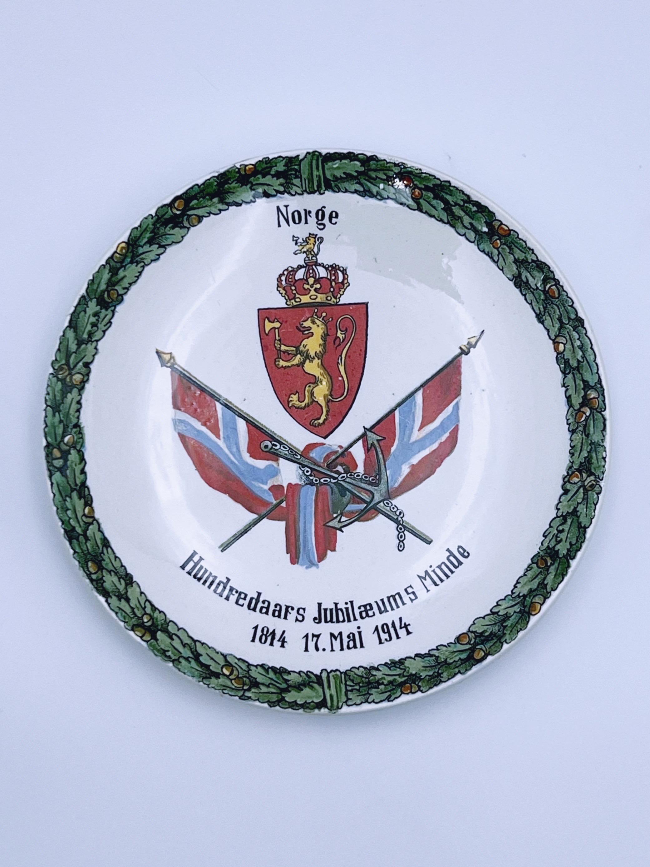 Antique wall-hanging plate / table decor / commemorative plate from 1914, marking the 100th anniversary of 1814 – 17. Mai / 17. May – 1914. 

Decorated with the Norwegian coat of arms, the lion, and the inscription 