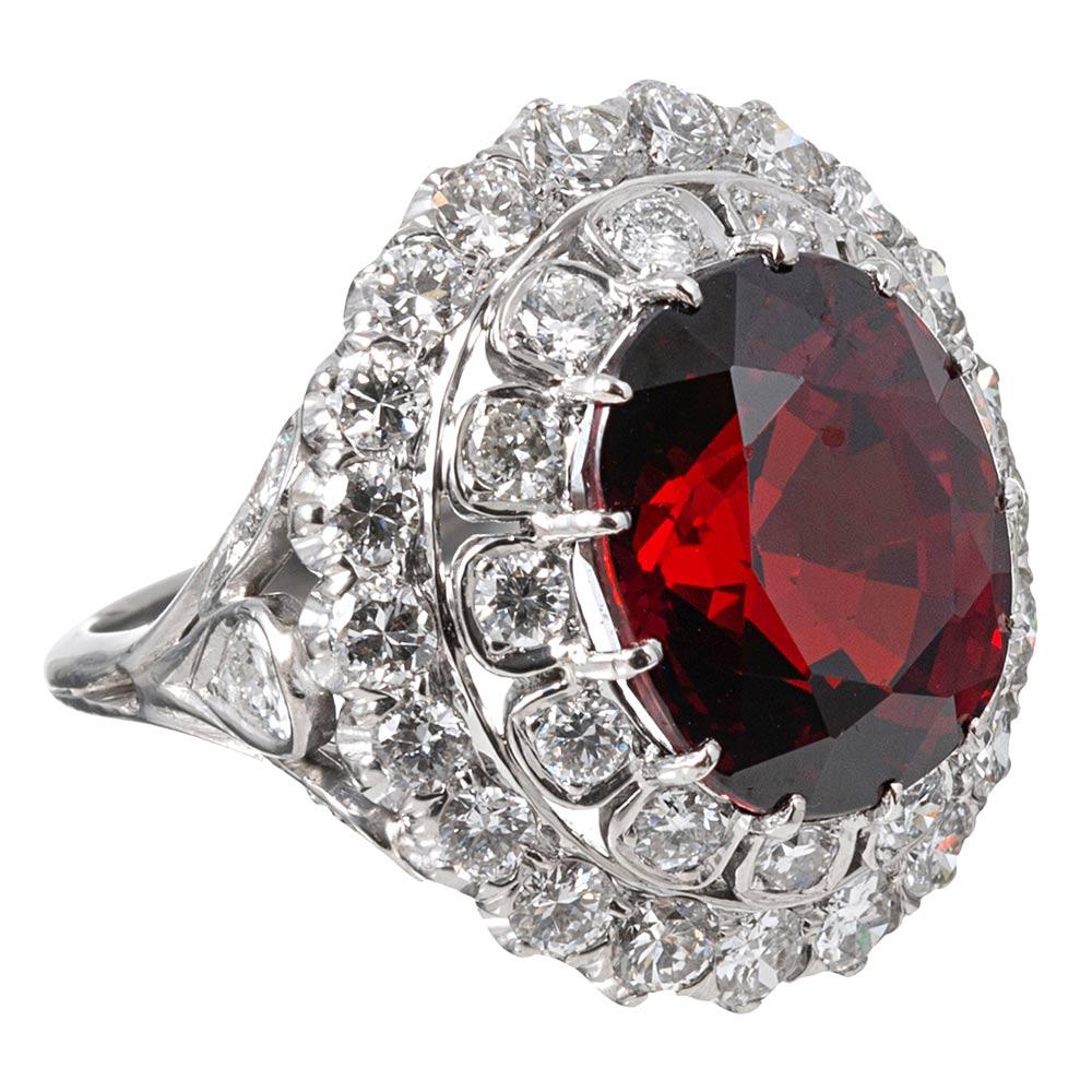 A beautiful cocktail ring with tiered rows of diamonds celebrating a large faceted oval spessartite garnet, the mounting made of platinum and decorated with approximately 4.00 carats of brilliant white diamonds. The major center stone weighs 18.14