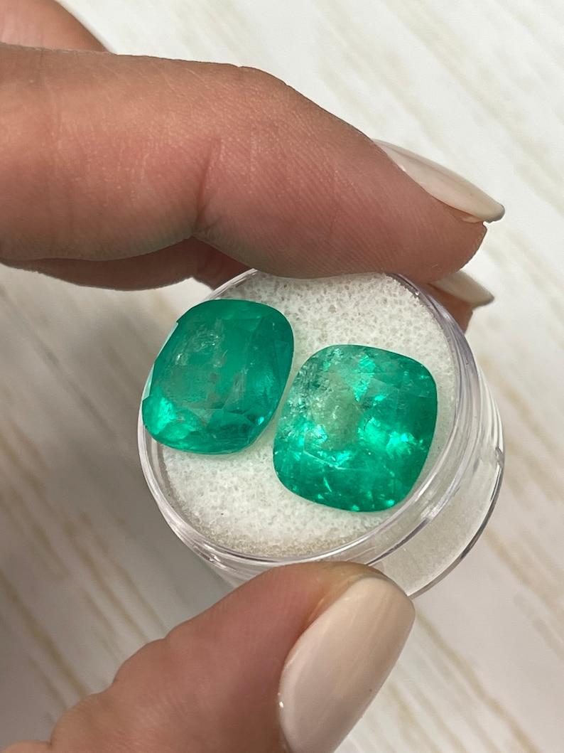 Pierre : Émeraude
Poids : 18,18 carats au total (les deux pierres précieuses combinées)
Forme : Coupe coussin
Clarté : Transparent, visiblement inclus
Lustre : Très bon
Couleur : Vert moyen
Dimensions : 14,02 mm x 13,0 mm x 9,23 mm // 13,62 mm x