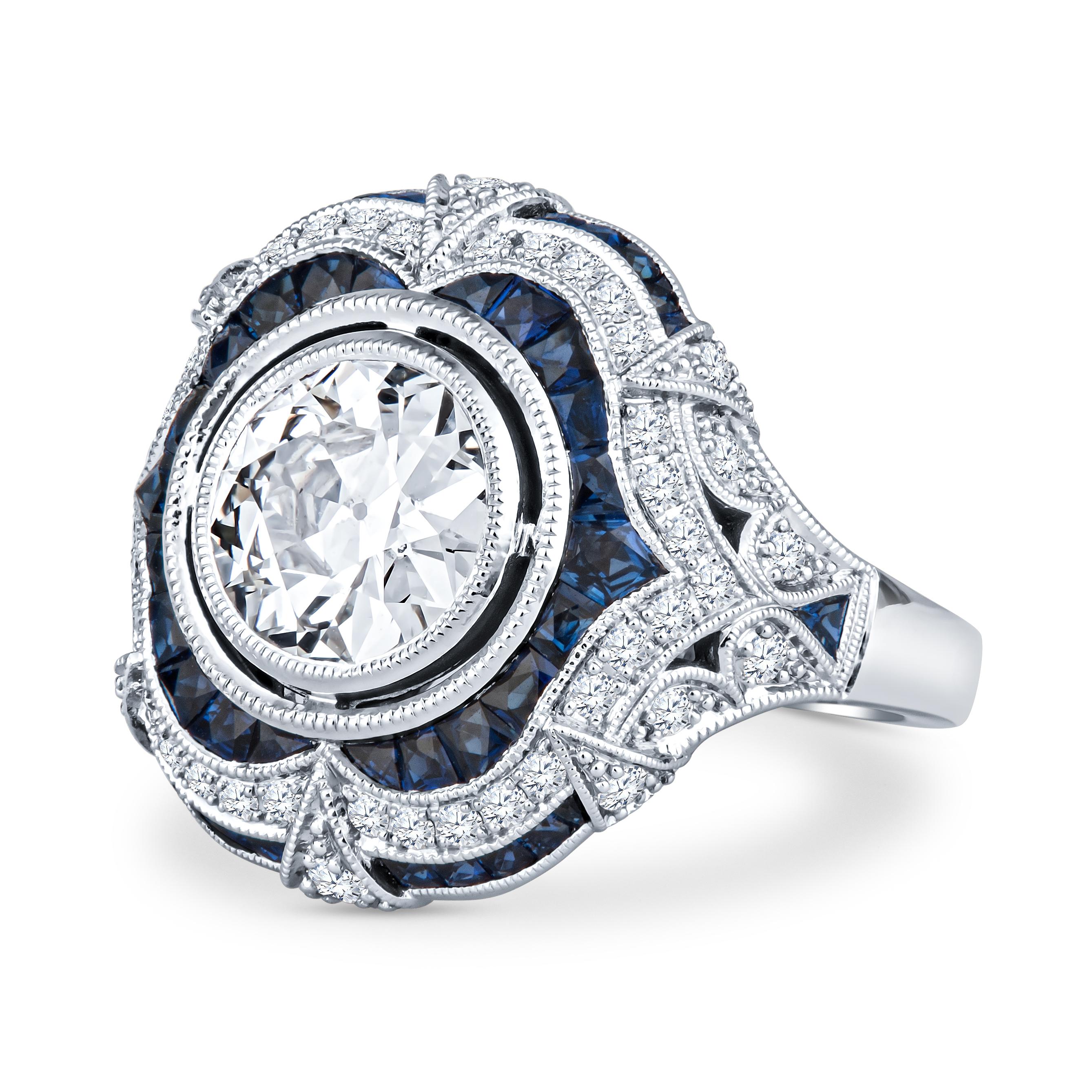 This exquisite Shaftel Diamonds 1.81ct Old European cut diamond (L SI1, GIA certified, GIA Report Number: 5201539315) is complemented by 1.21ct total weight in natural blue sapphires adorning the ring, alongside 0.42ct total weight in side diamonds.