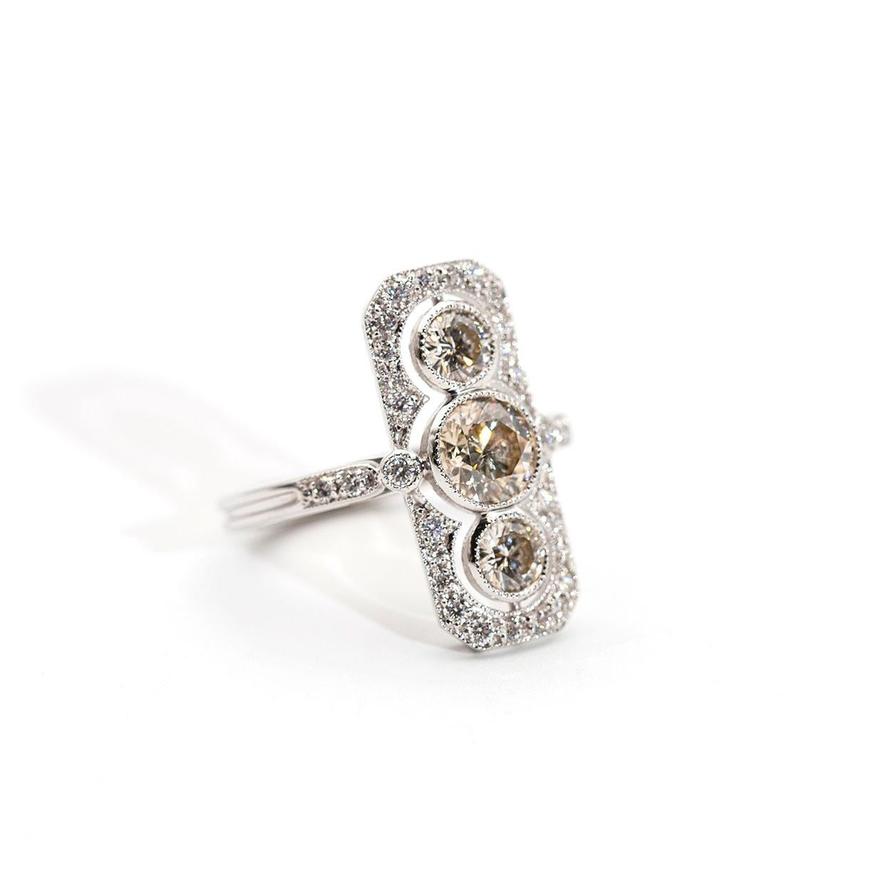 This art deco inspired three stone ring is forged 18 carat white gold and boasts a total of 1.82 carats of alluring bright round brilliant cut diamonds with the largest centre diamond certified. The featured three diamonds come to life with the