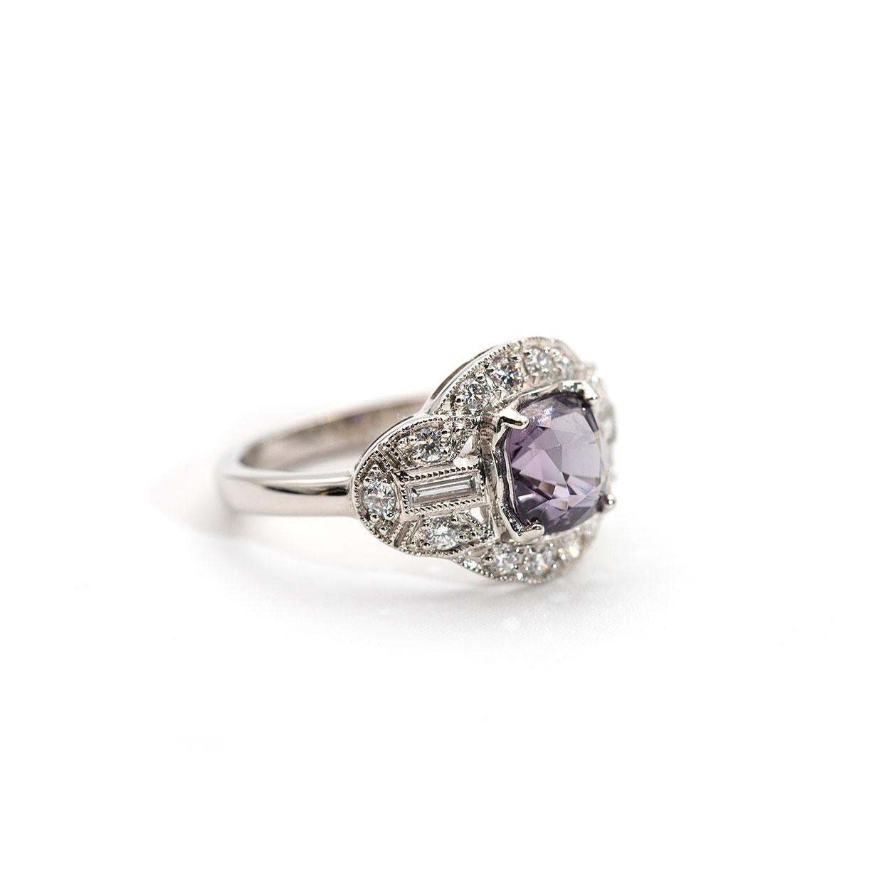 This vintage inspired spinel and diamond ring forged in platinum features an enchanting 1.82 carat greyish purple cushion cut spinel and is circled by a total 0.40 carats of round brilliant cut diamonds and baguette cut diamonds. We have named this
