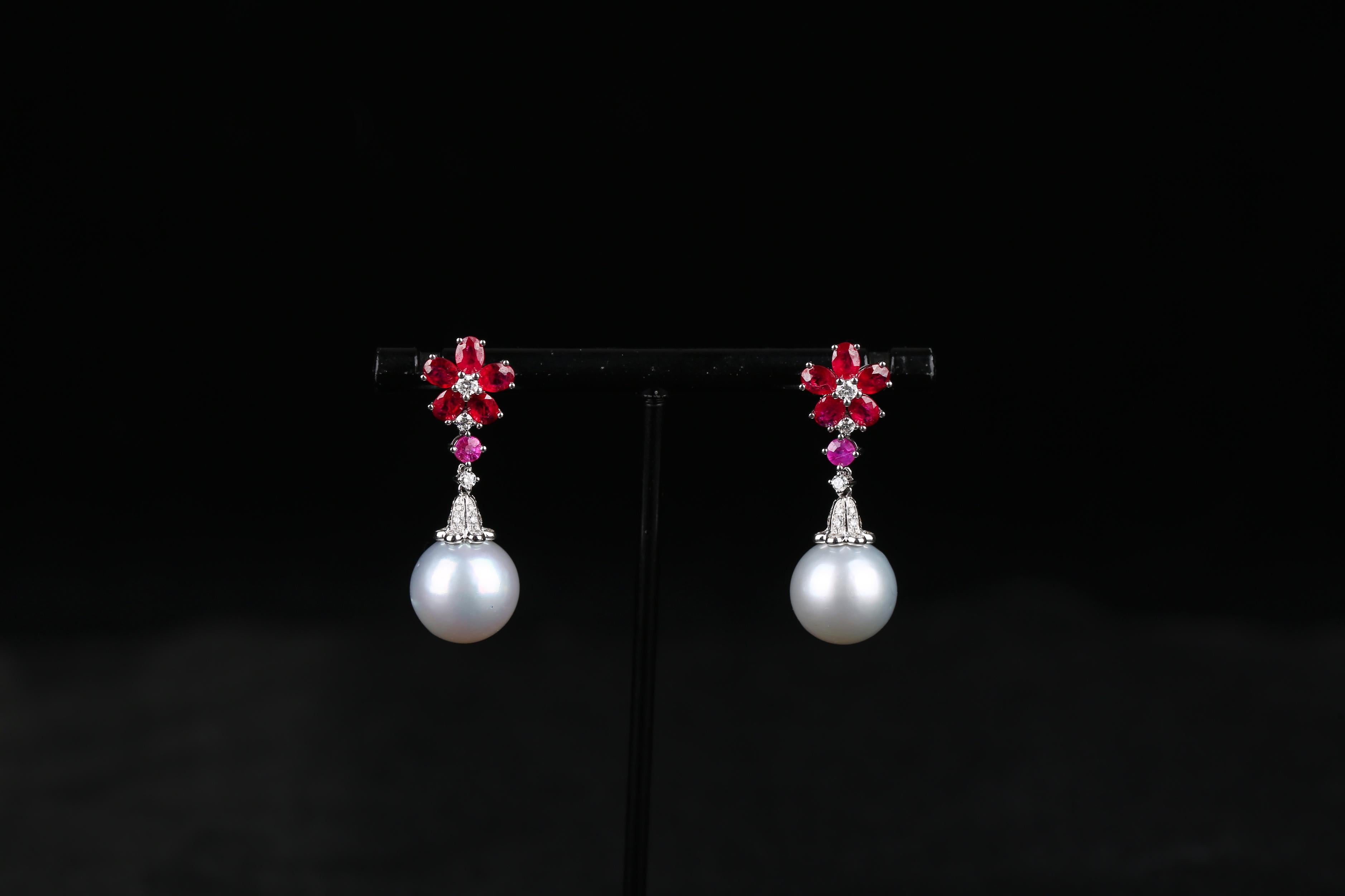 This is a pair of flower motif South Sea Pearl Earring. The flower petals are made of 5 oval rubies and a round diamond at the center of the flower. The White South Sea Pearl is then suspended below the Pink Sapphire and Diamond Bale. It is a simple