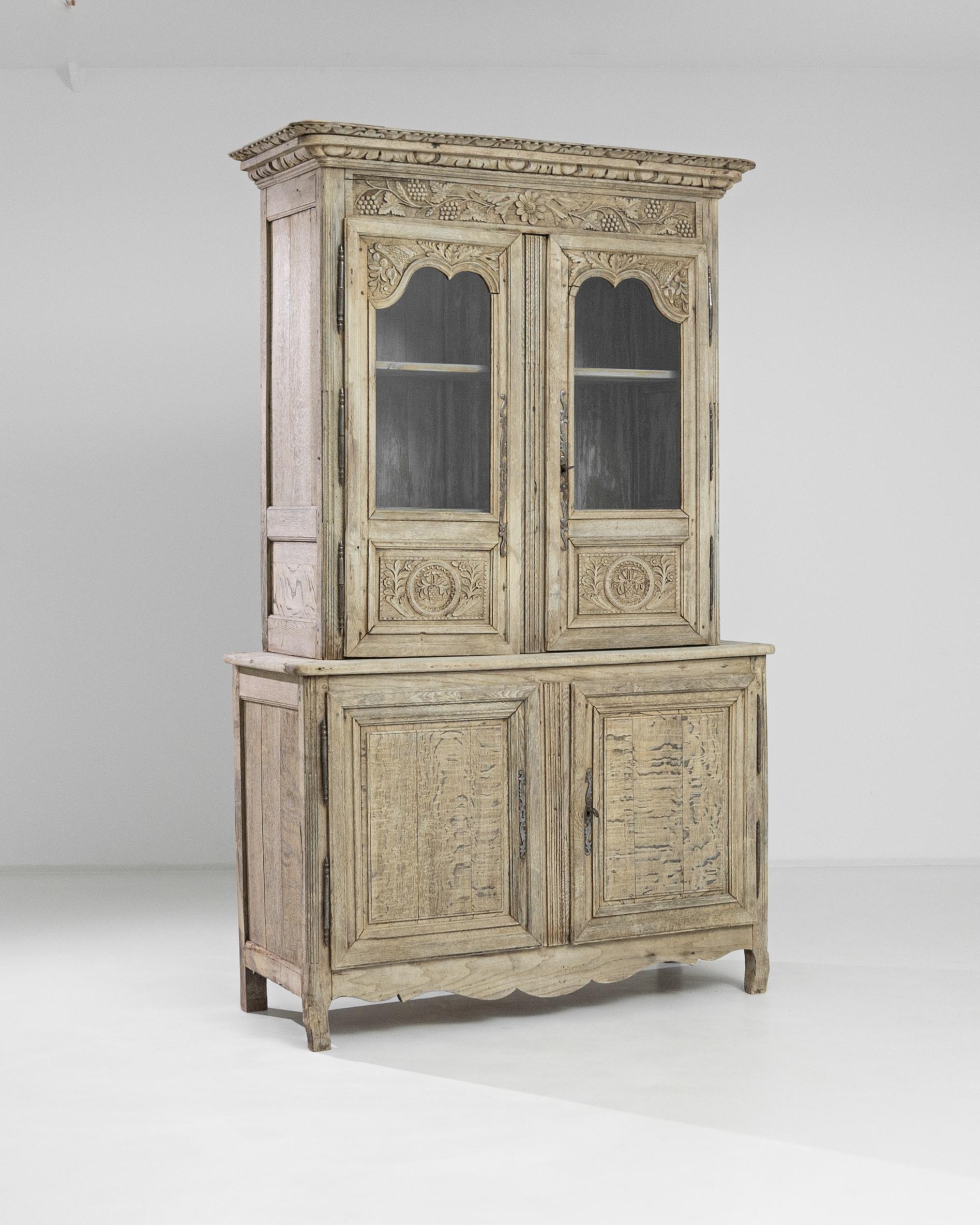 This antique cabinet was produced in France, circa 1820. Composed of a vitrine standing on top of a buffet, this wooden cabinet features bracket feet, a scalloped apron, hidden drawers and a heavily ornamented top case crowned by a florid molded