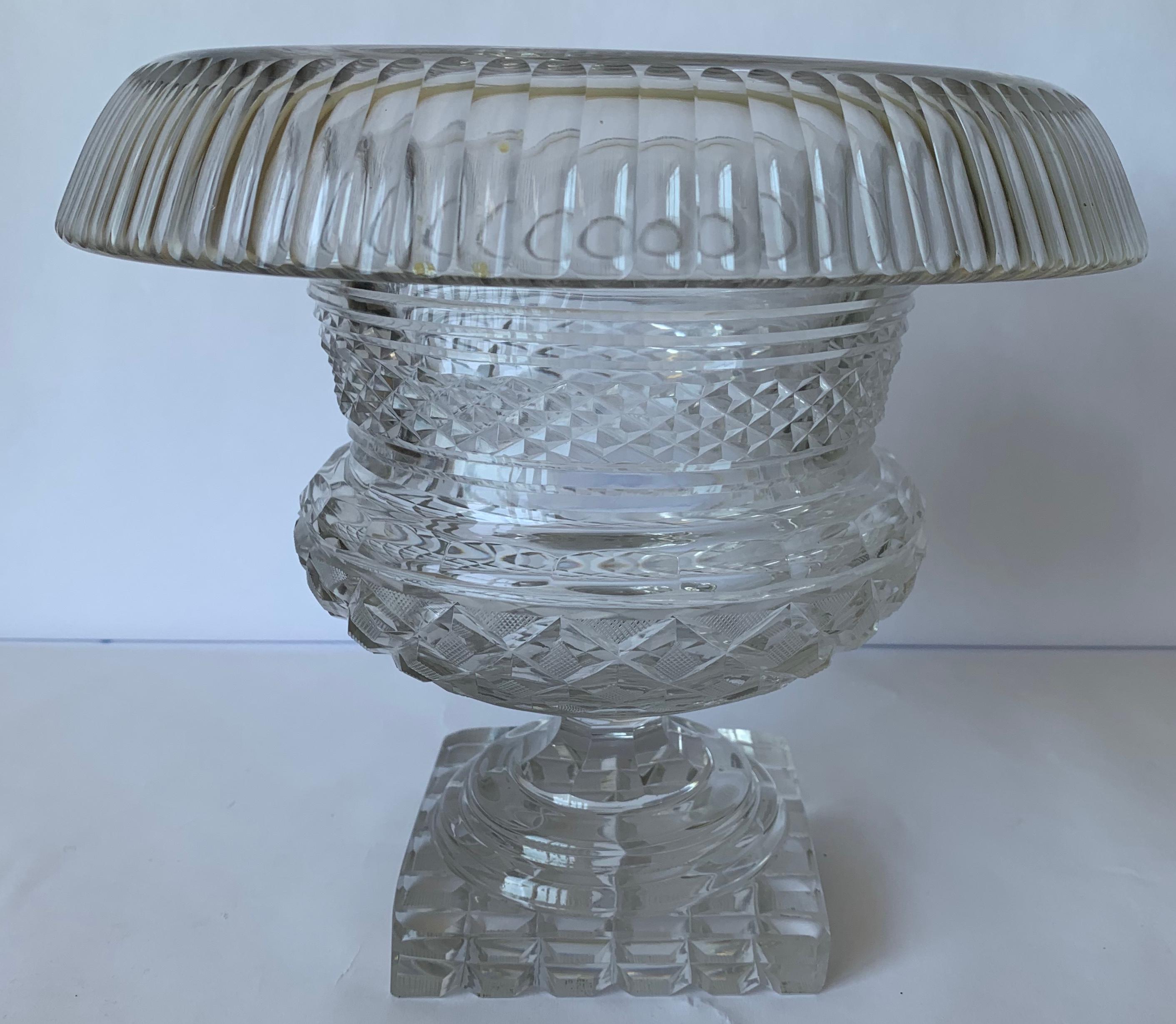 Anglo-Irish cut crystal footed center bowl circa 1820. Excellent cutting throughout with unusual rolled and turned fluted edge. Campana form with round stepped base on square plinth. Strawberry diamond cutting on bowl and bottom. No makers mark or