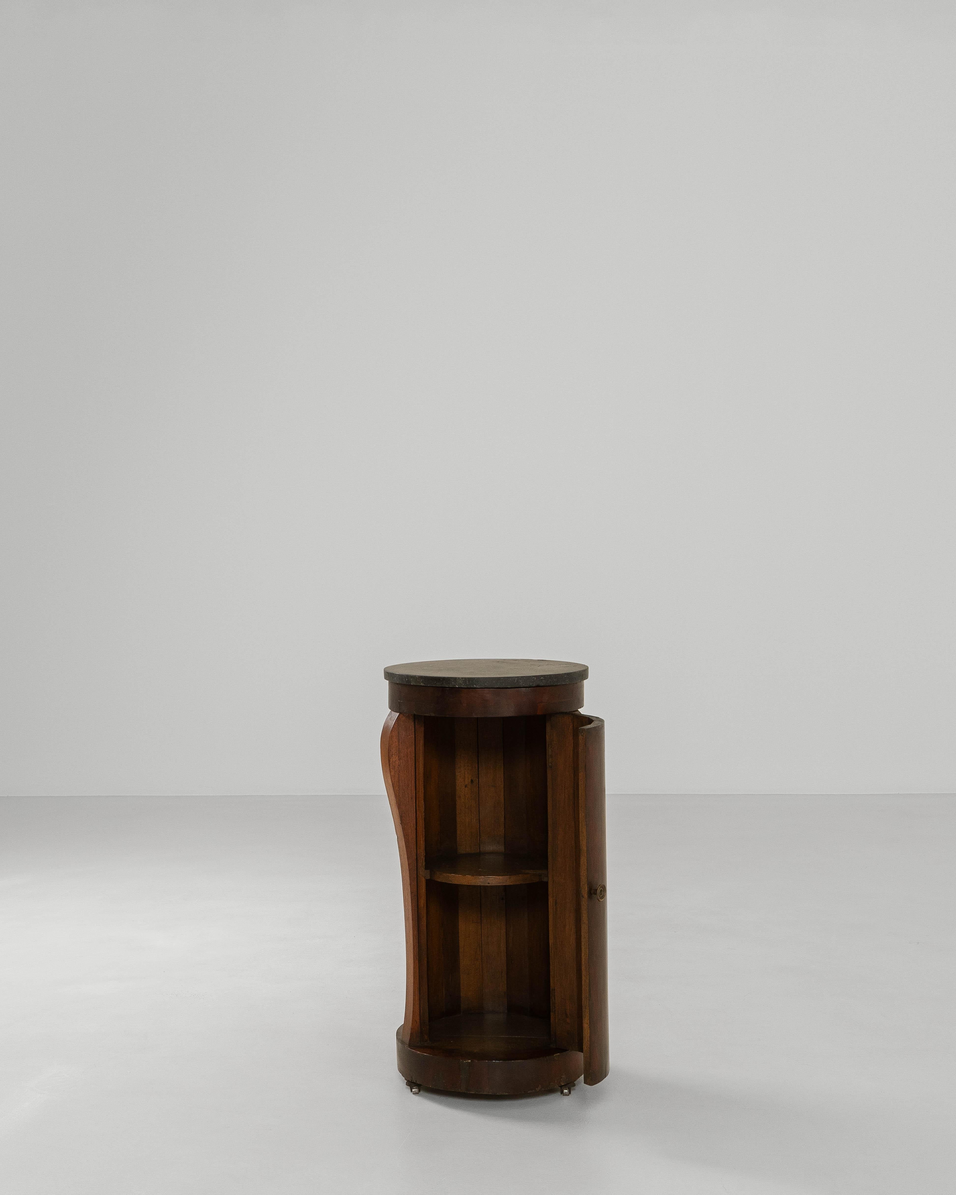 This 1820s Belgian Empire mahogany cabinet exemplifies the refined restraint and architectural clarity associated with early 19th-century Empire design. Crafted from richly toned mahogany, the cabinet features a graceful cylindrical form accented by