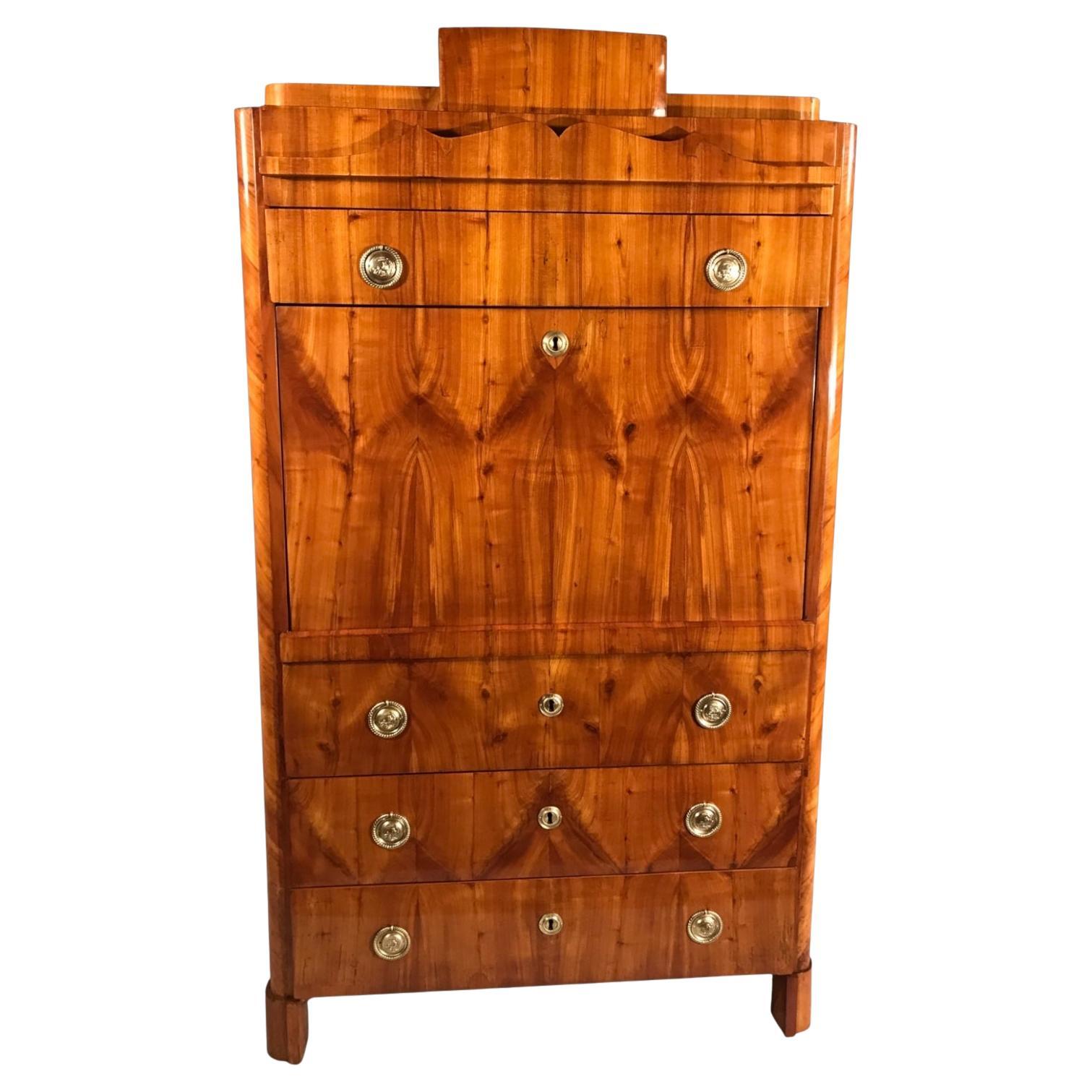 1820’s Biedermeier Fall Top Desk in Cherry Veneer
The 1820’s Biedermeier fall top desk features stunning book-matched cherry veneer, adding warmth and sophistication. Its lower section consists of three spacious drawers, while the upper part